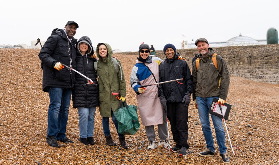 Six Nestlé employees stand on Brighton Beach with litter pickers and rubbish bags