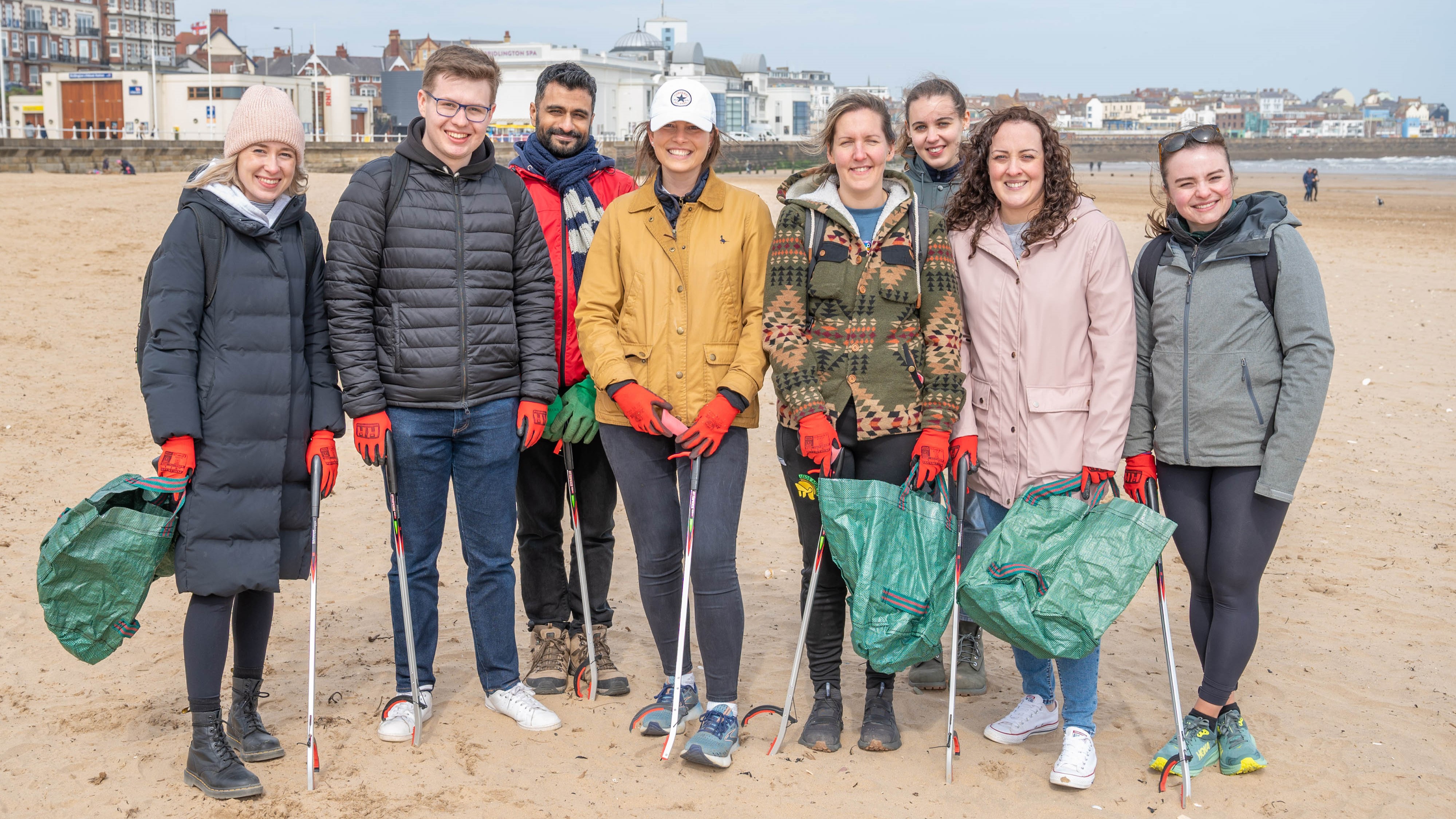 A group of colleagues from Nestlé York on Bridlington beach with litter picks and bin bags.