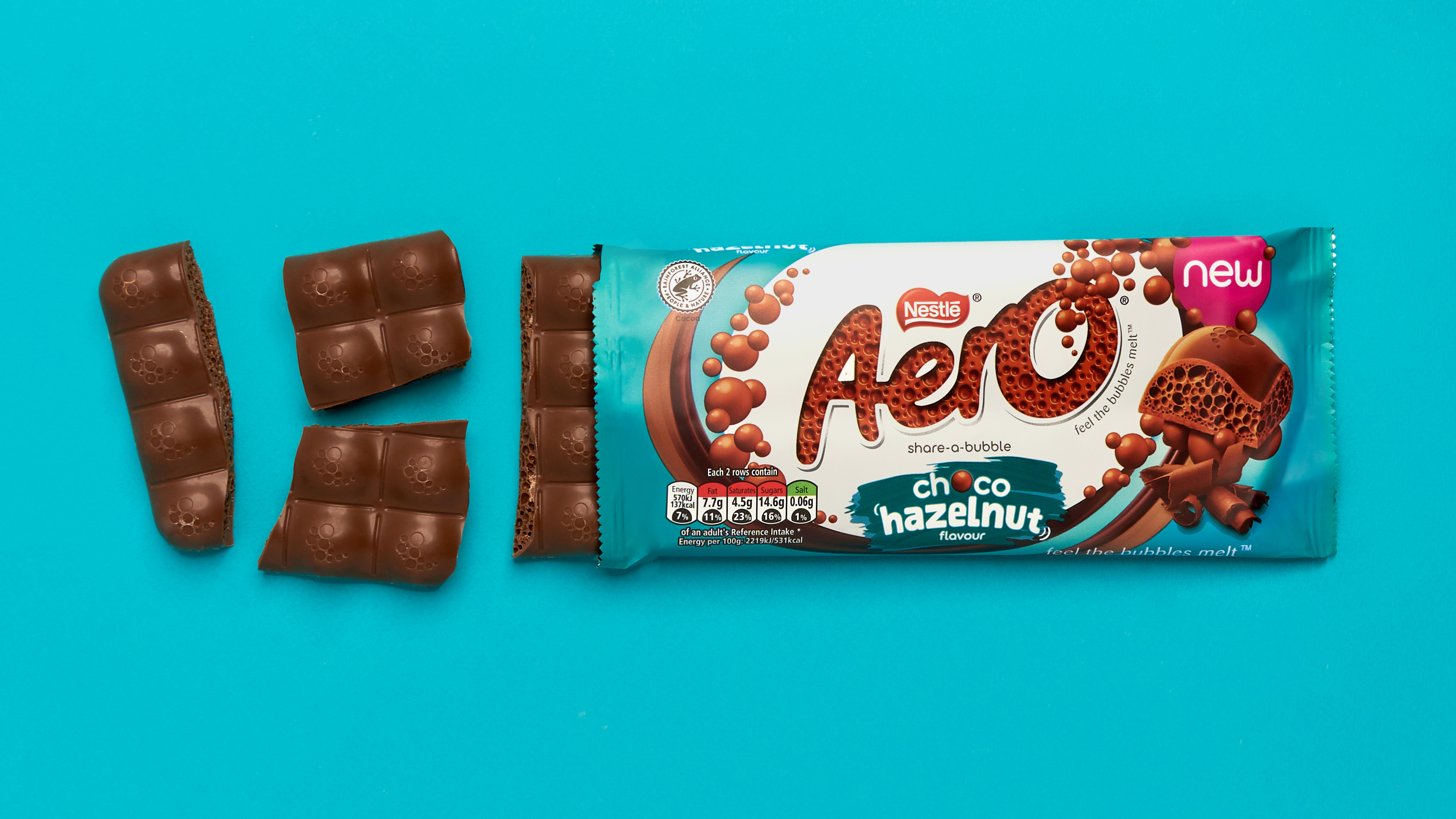 Sections of an Aero chocolate bar peeking out of an Aero choco-hazelnut flavour bar on a teal background.
