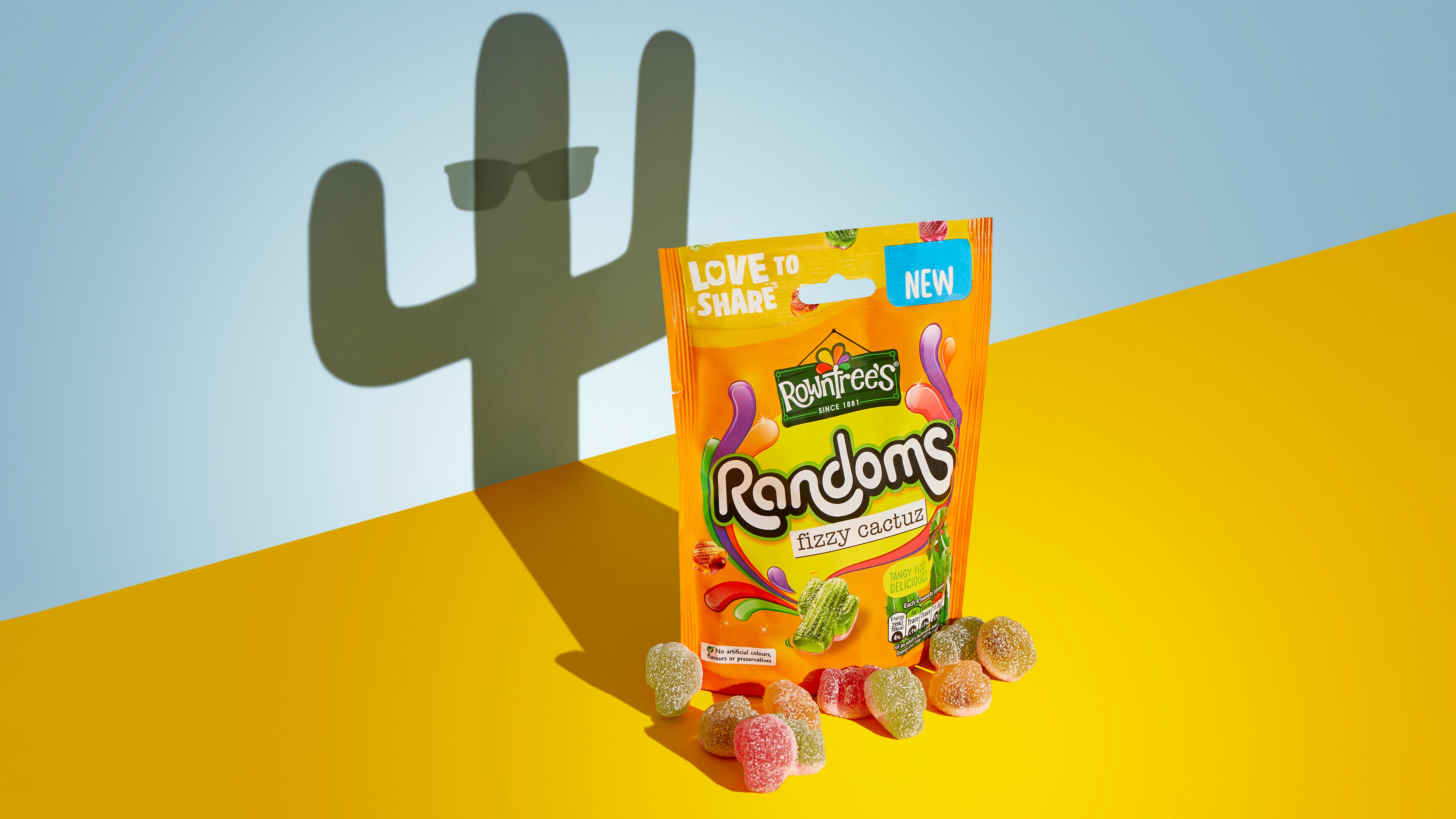 An orange packet of sweets, with some colourful sweets sitting in front of it, and a cactus-shaped shadow behind it.