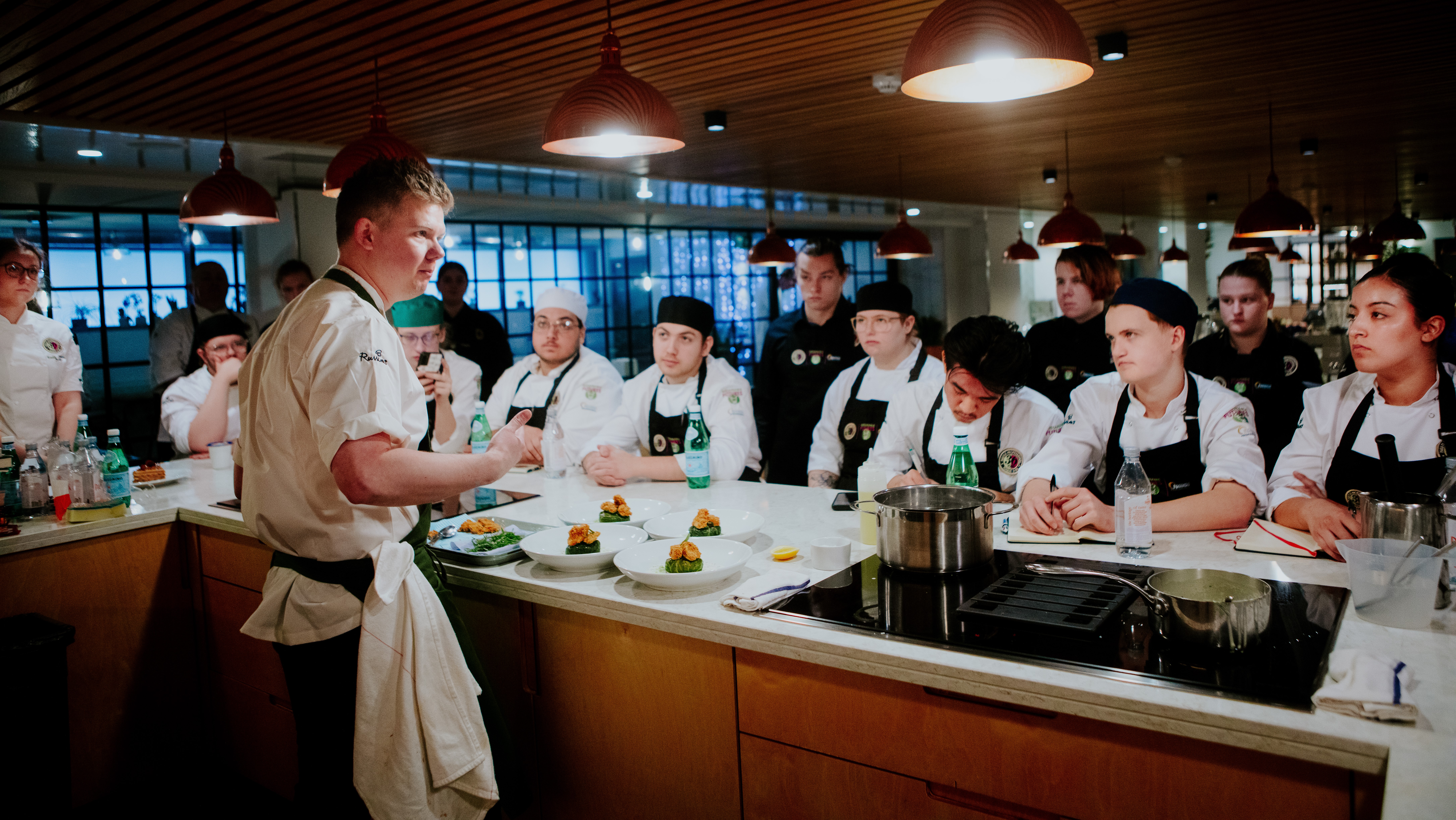 A Toque d'Or chef giving a demonstration in front of an audience of cooks. 