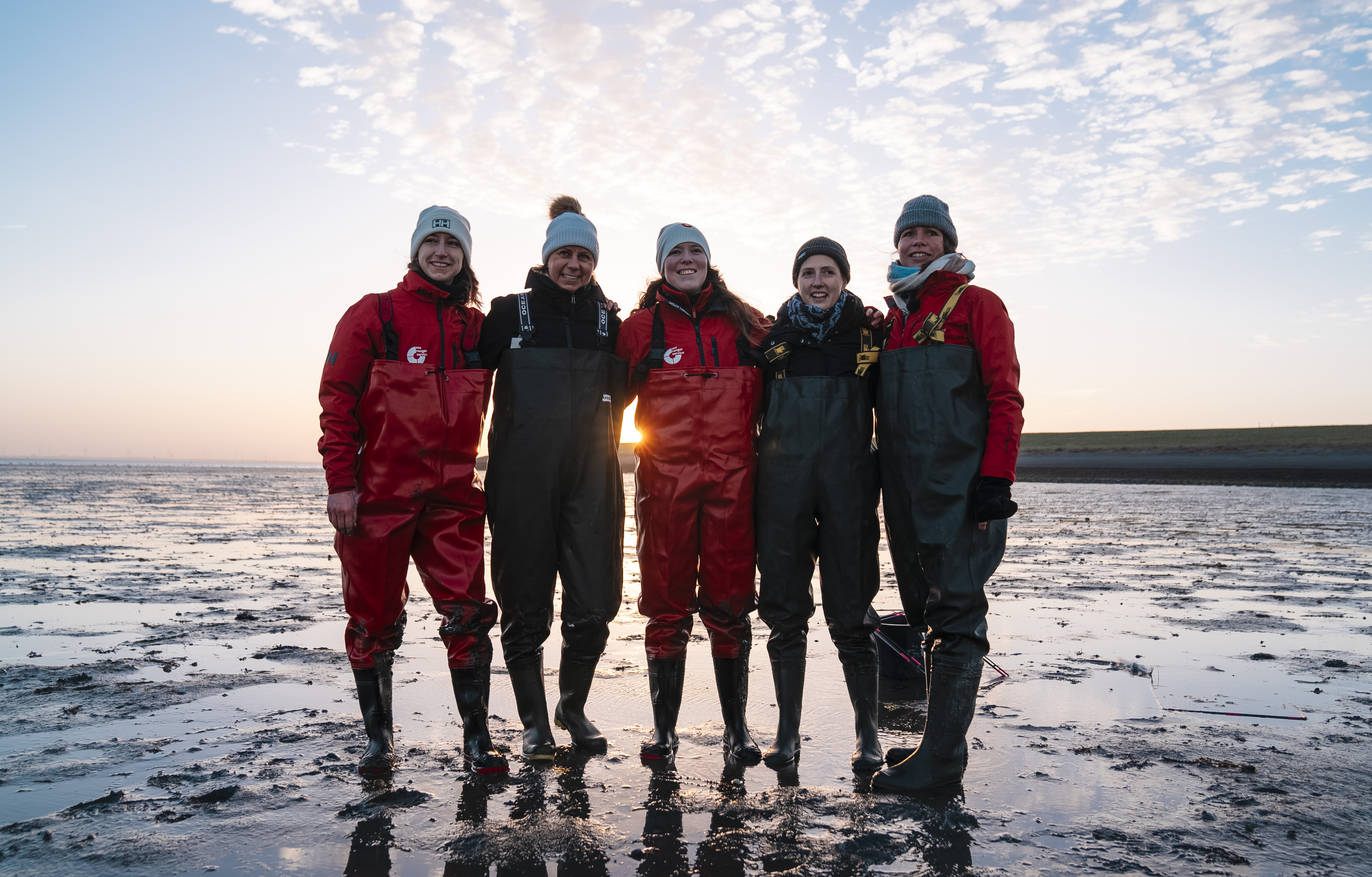 A group of five sea rangers standing together against an ocean backdrop.