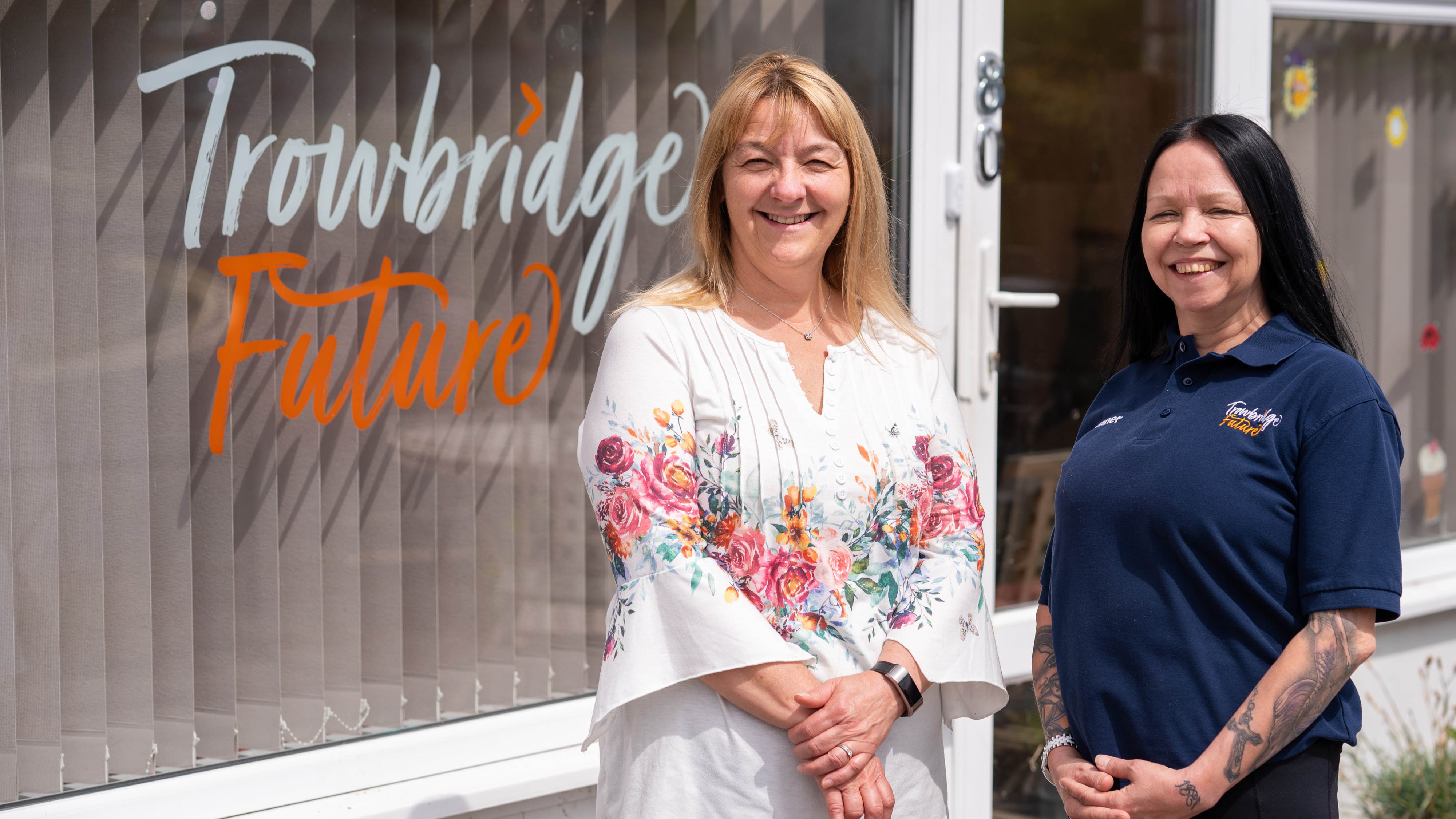 Two women standing outside of a community cafe.
