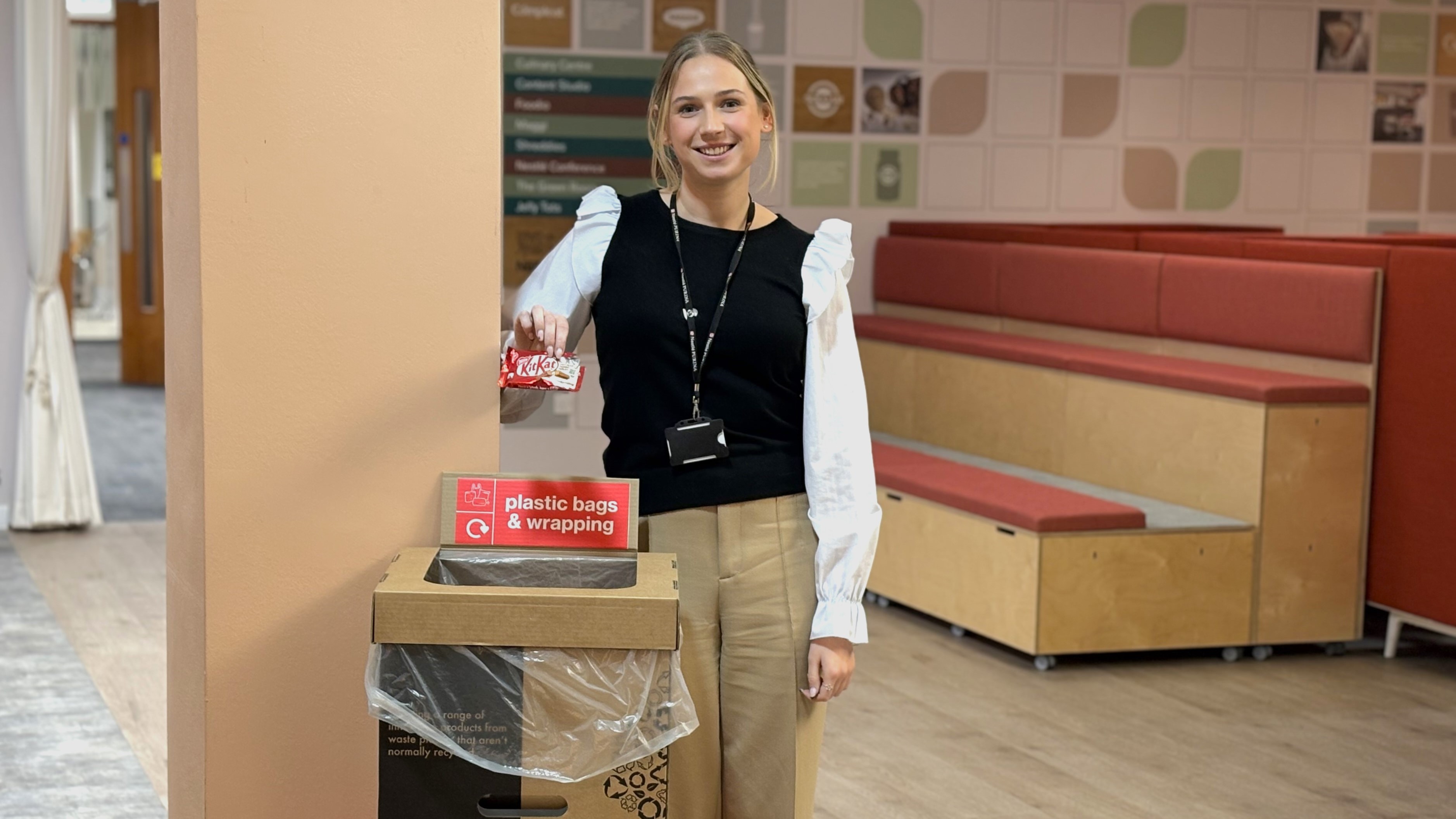 Young woman holding packaging over a recycling bin.