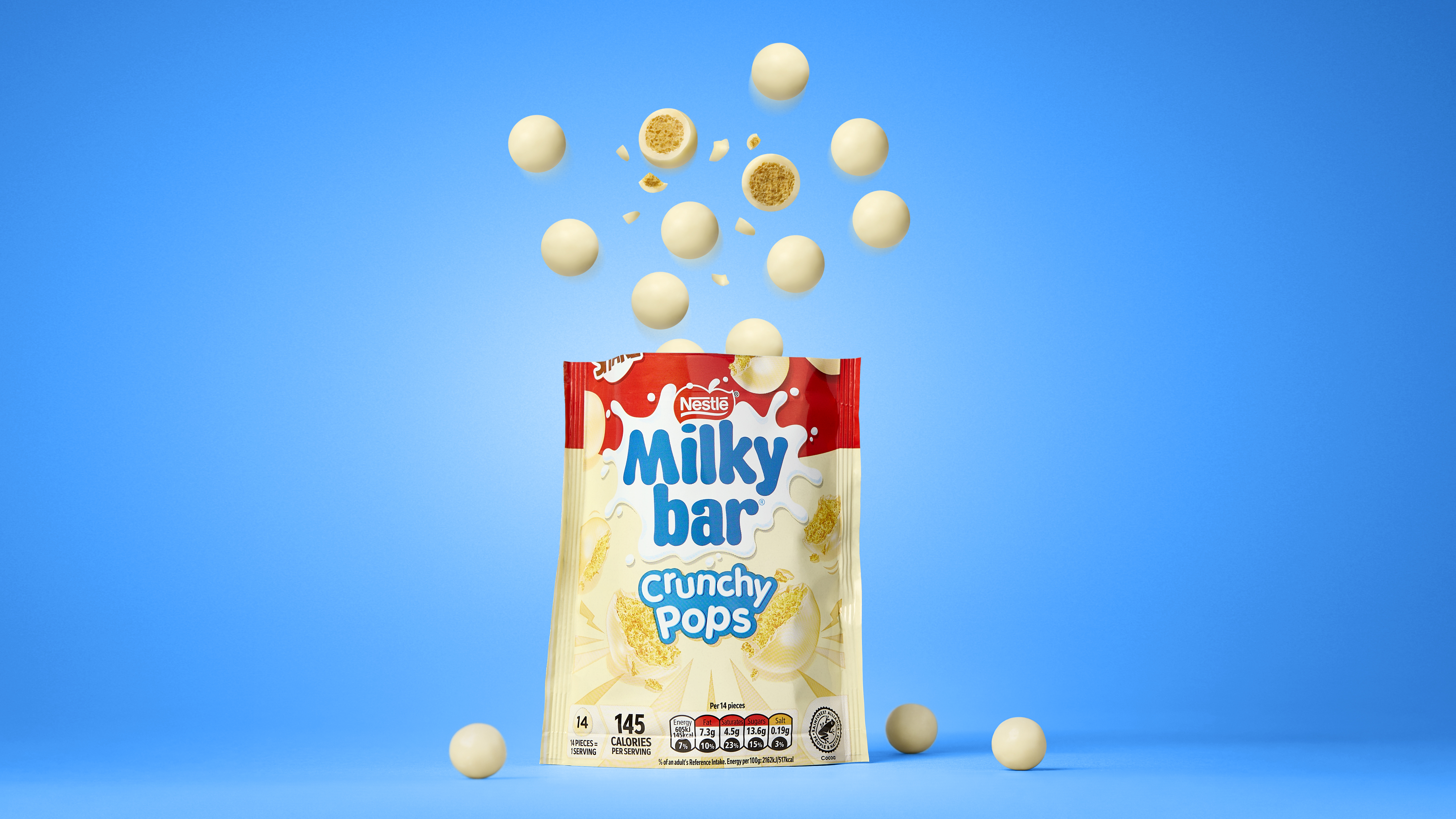 Milkybar Crunchy Pops jumping out of the packet with a blue background