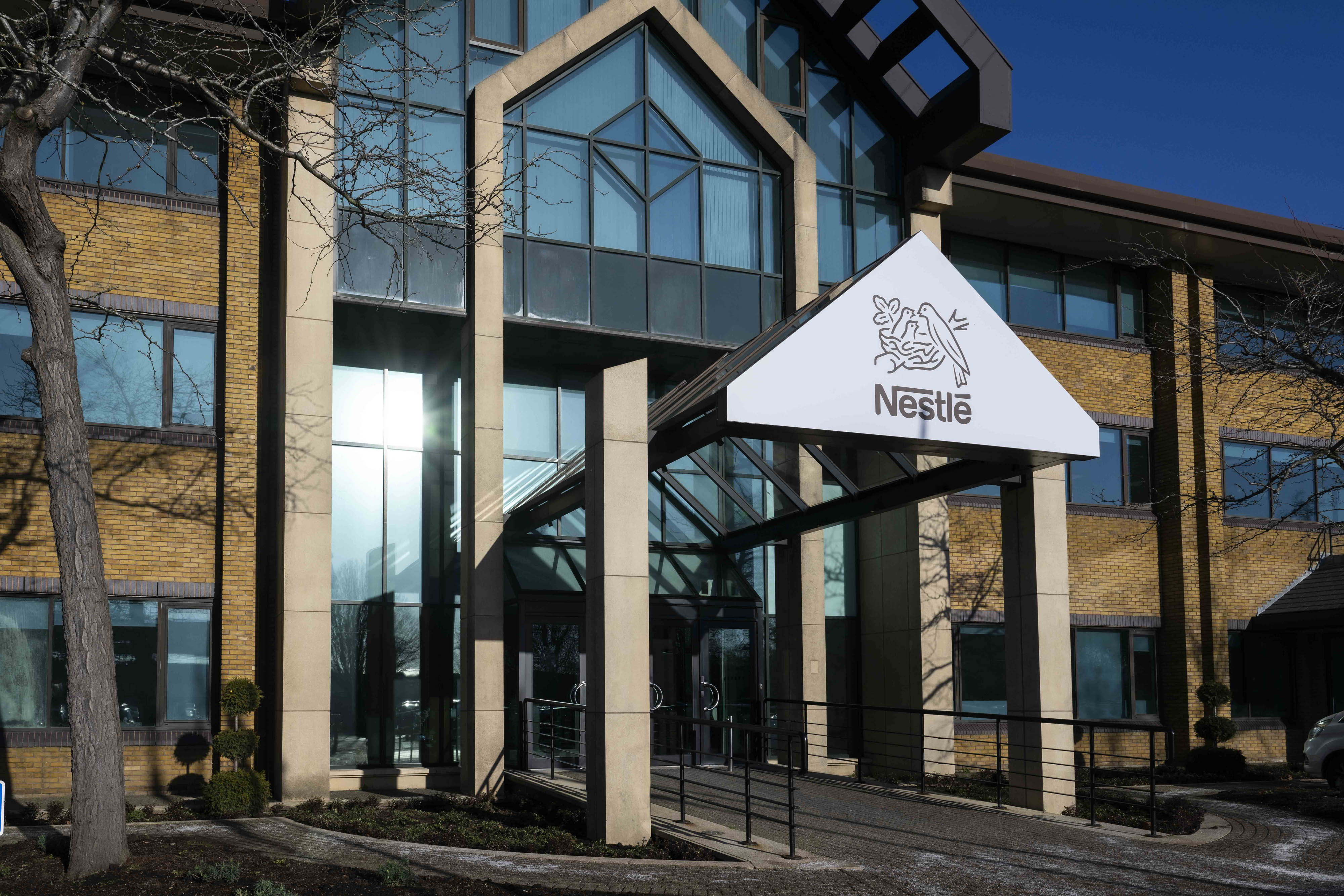 Outside shot of Nestlé office building with logo above the entrance doors. 