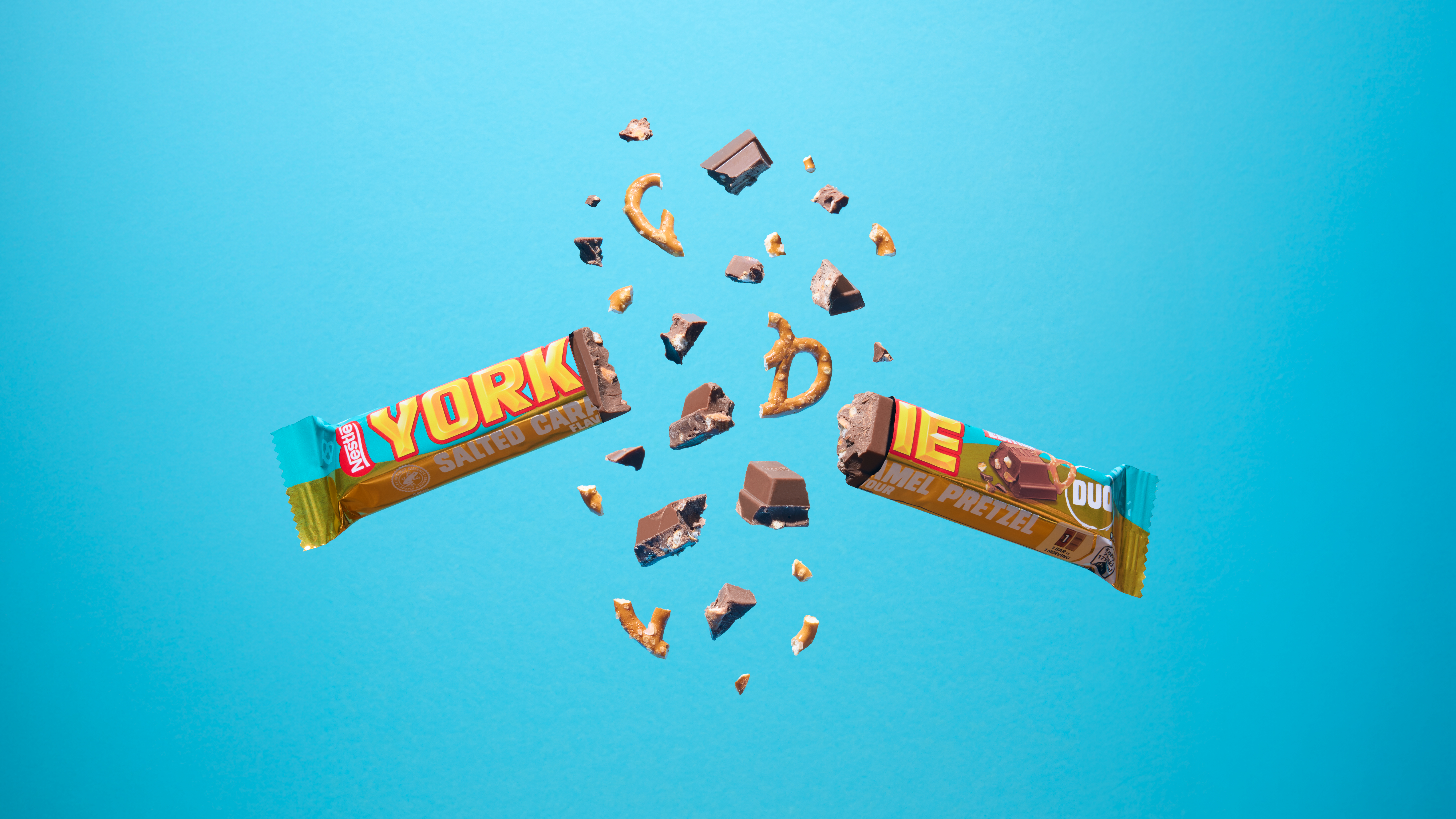 Yorkie Salted Caramel Pretzel Duo bar floating in front of a blue background, split in half with chocolate and pretzel pieces