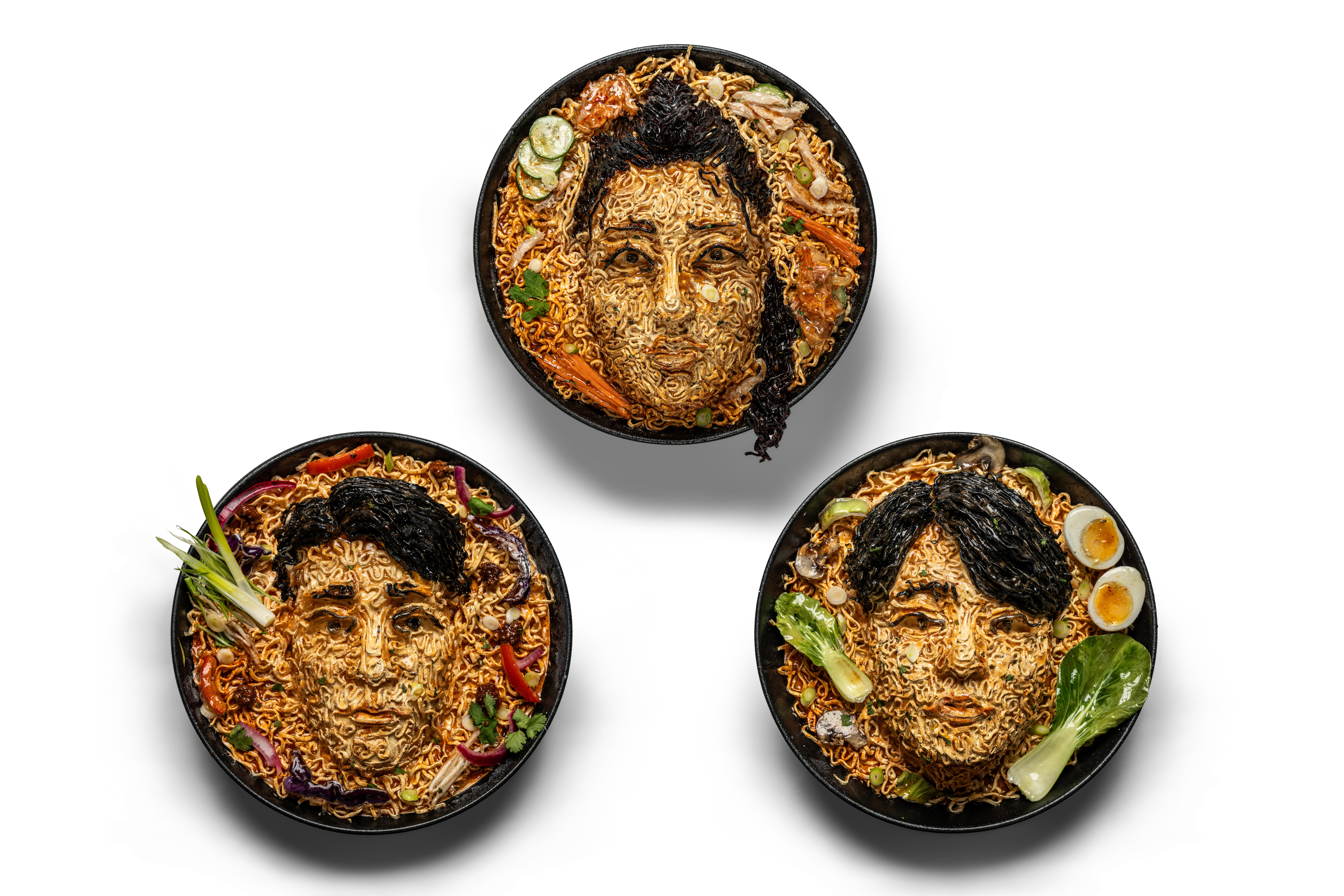 Three bowls featuring portrait artworks inside them made of noodles, inspired by Kim Eun-jae, Jung Kook and Son Heung-min.