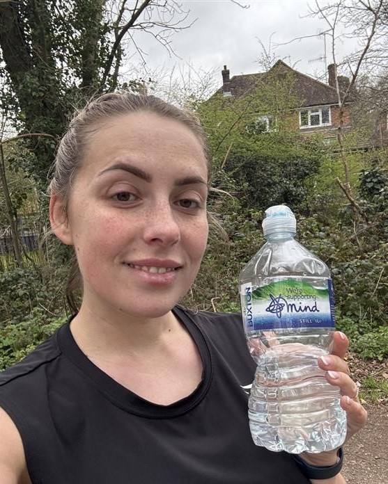 Woman holding a Buxton water bottle whilst out for a run.