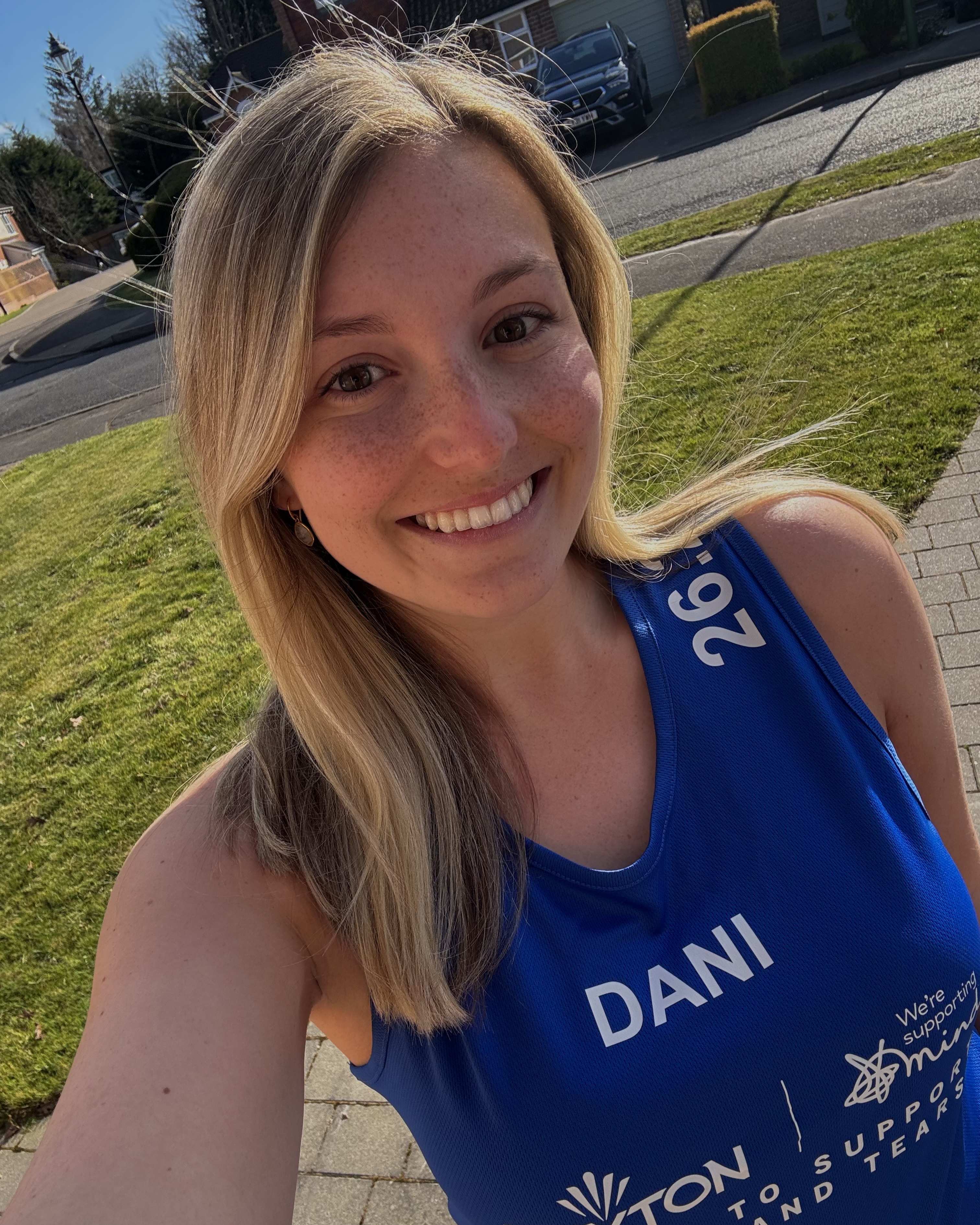Young woman in athletic clothing standing outside.