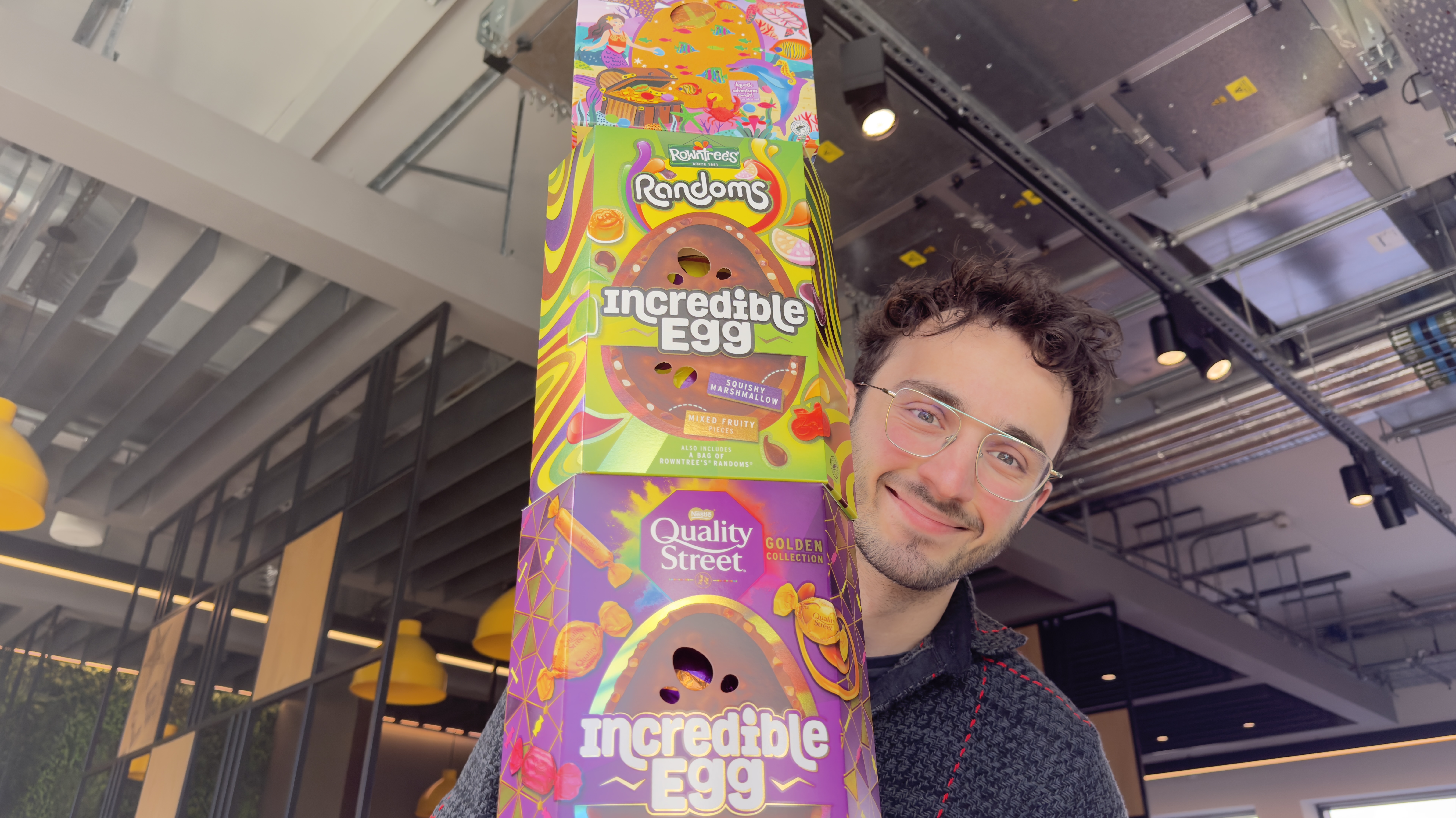 Man smiling beside a stack of Easter eggs.