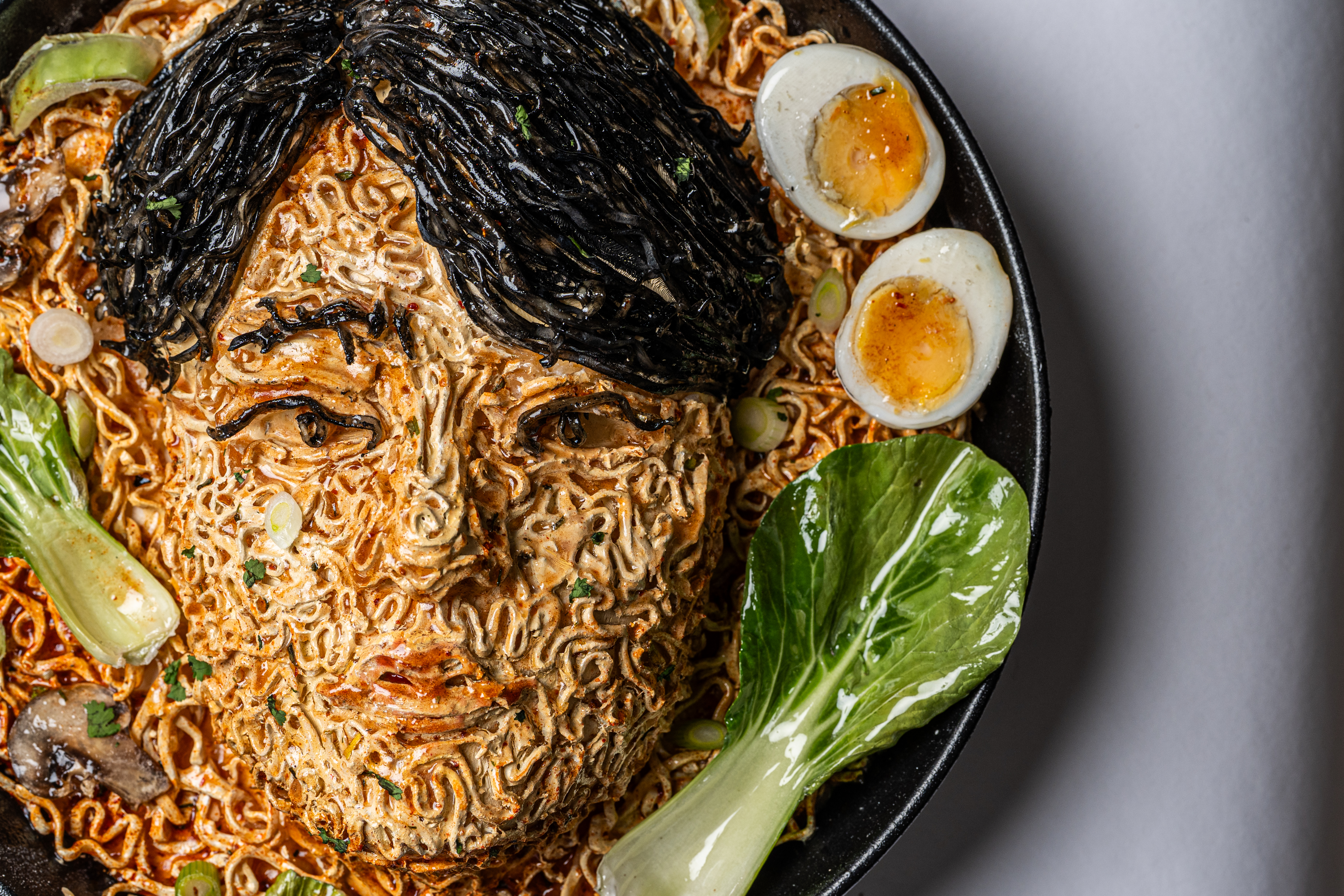 An portrait artwork created by noodles and ingredients including egg and pak choi inspired by BTS's Jung Kook.