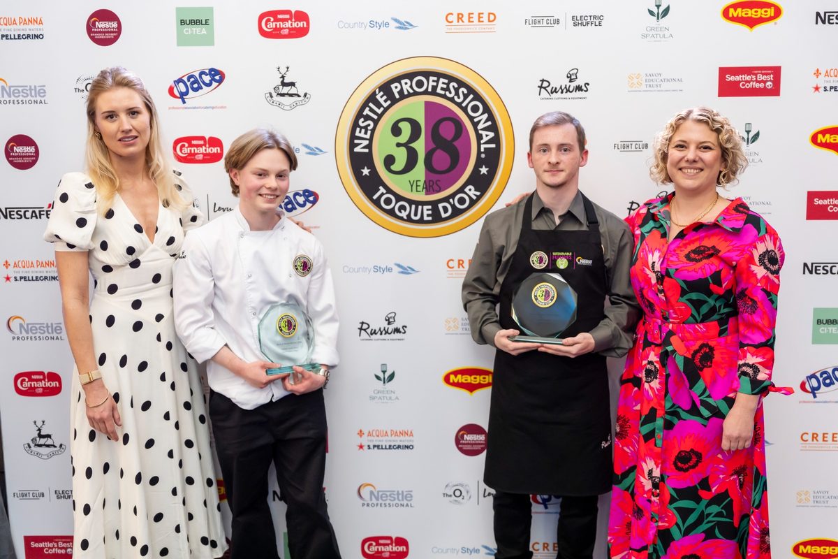 Four people, including two winners in the middle holding awards, standing in front of a branded Nestlé Professional wall.
