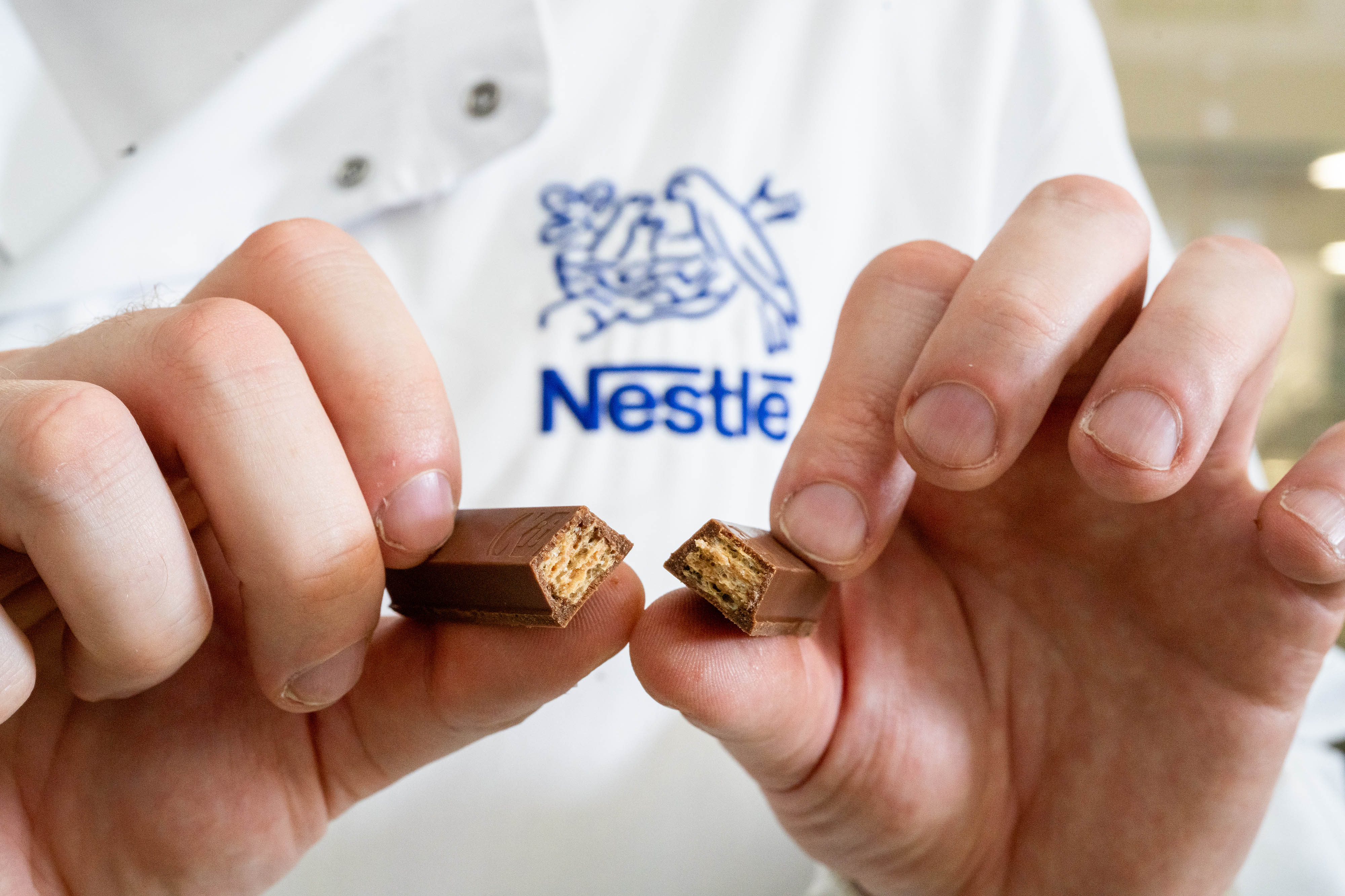 Hands holding a snapped-in-half KitKat bar to show the wafer.