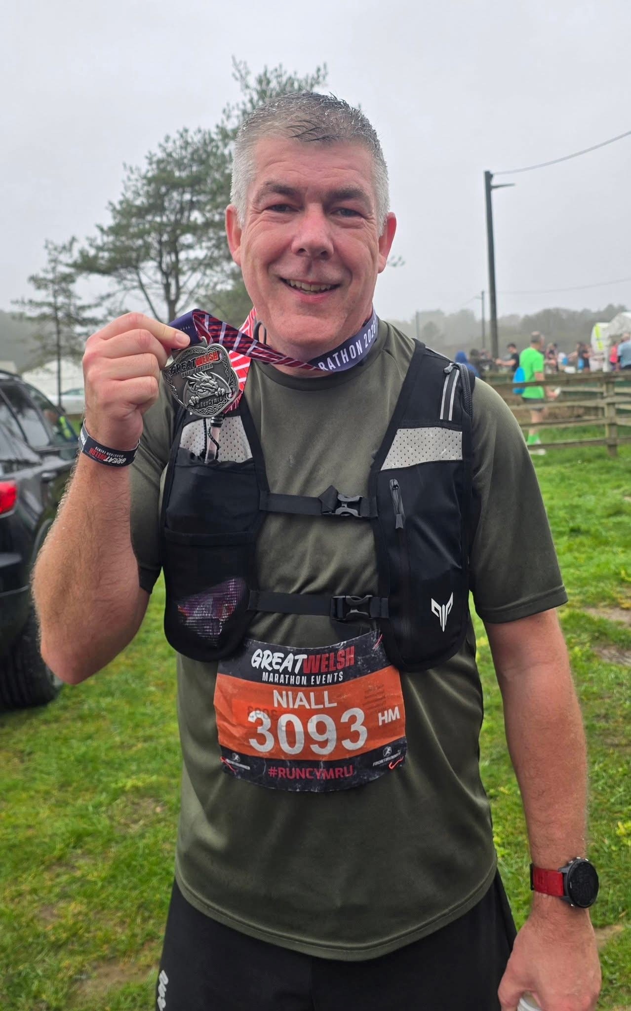 Man holding medal after a run.