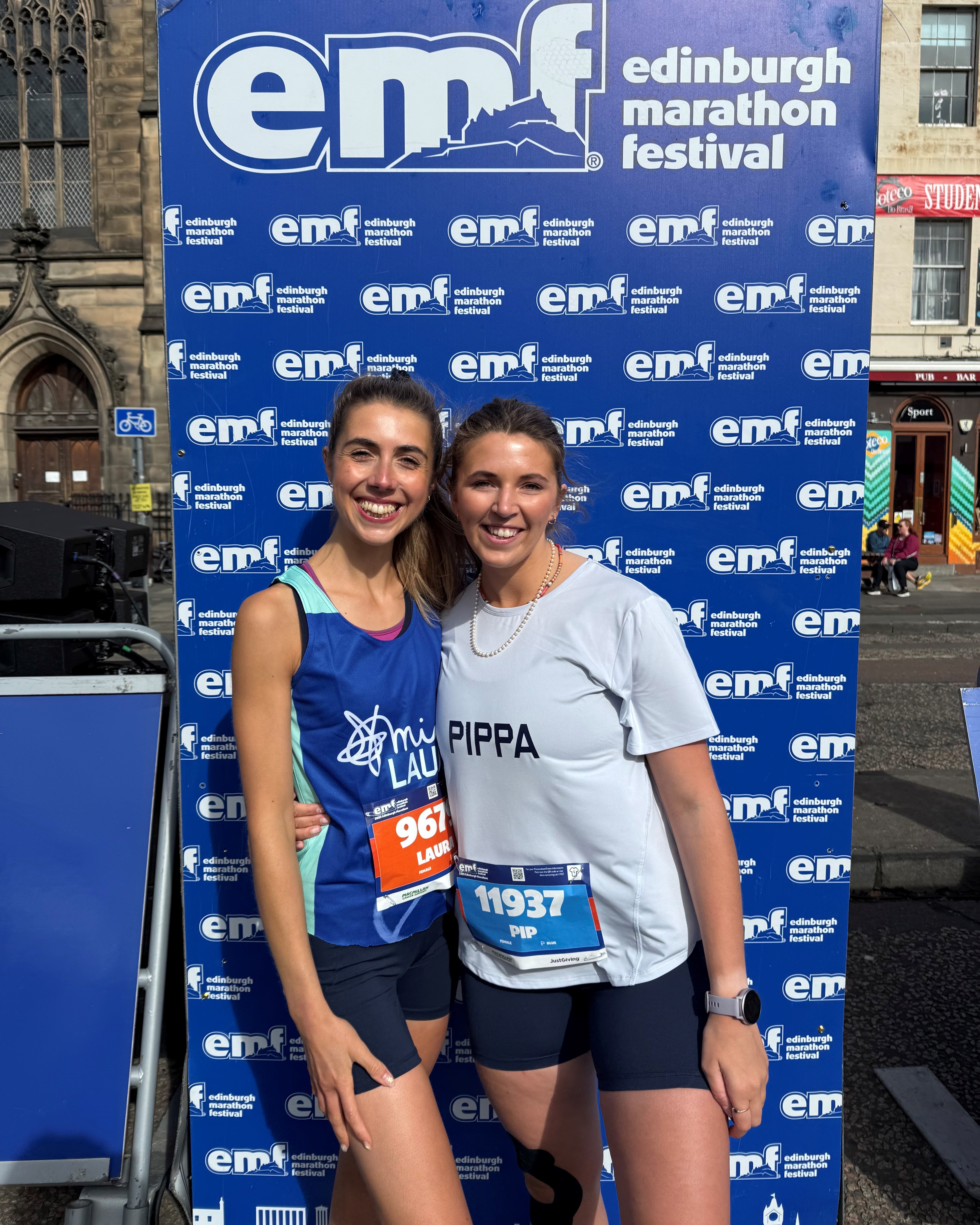 Two women stood in front of an Edinburgh Marathon Festival sign.