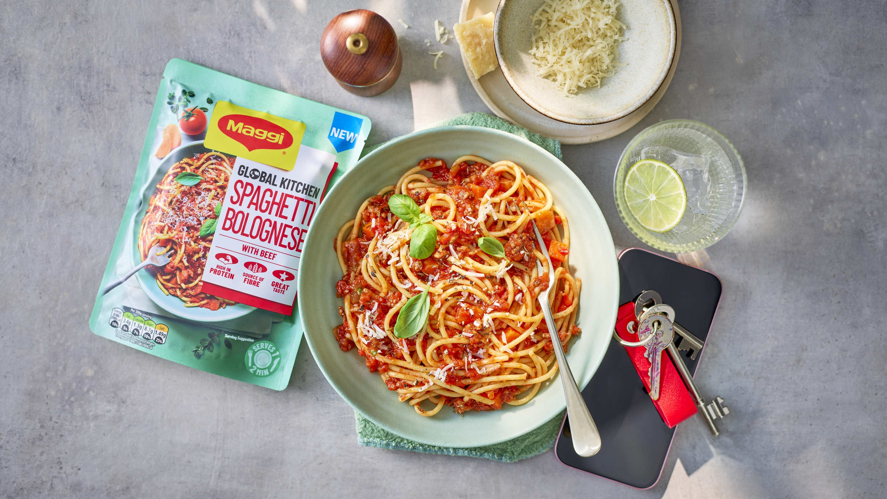 Bowl of Spaghetti Bolognese on a busy kitchen worktop next to the ready meal pouch.