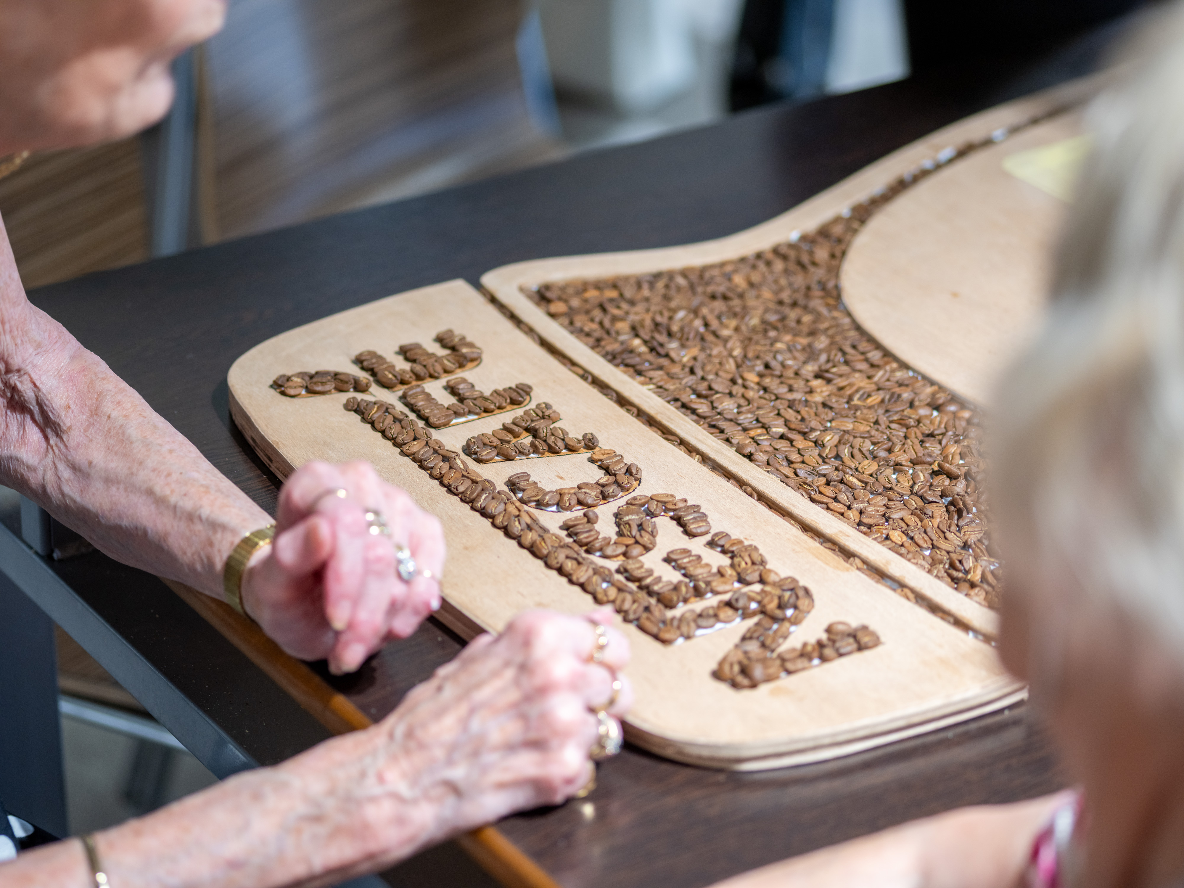 A landscape image of a woman's hands next to a homemade Nescafé sign made of coffee beans.