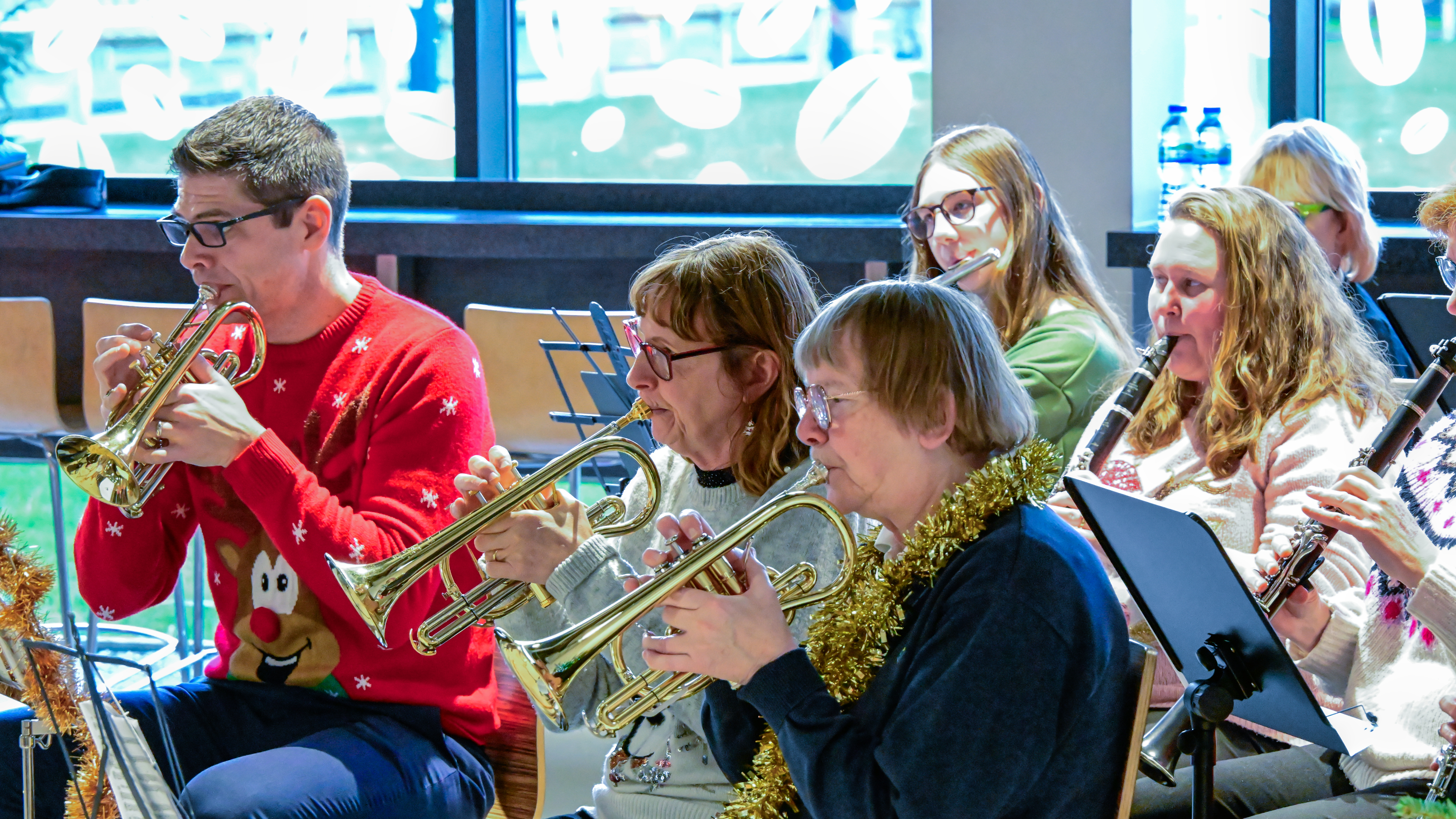 A landscape image of a wind pipe band, all dressed in festive jumpers and hats.