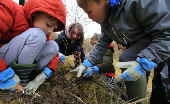 four children gardening with gloves and a trowel