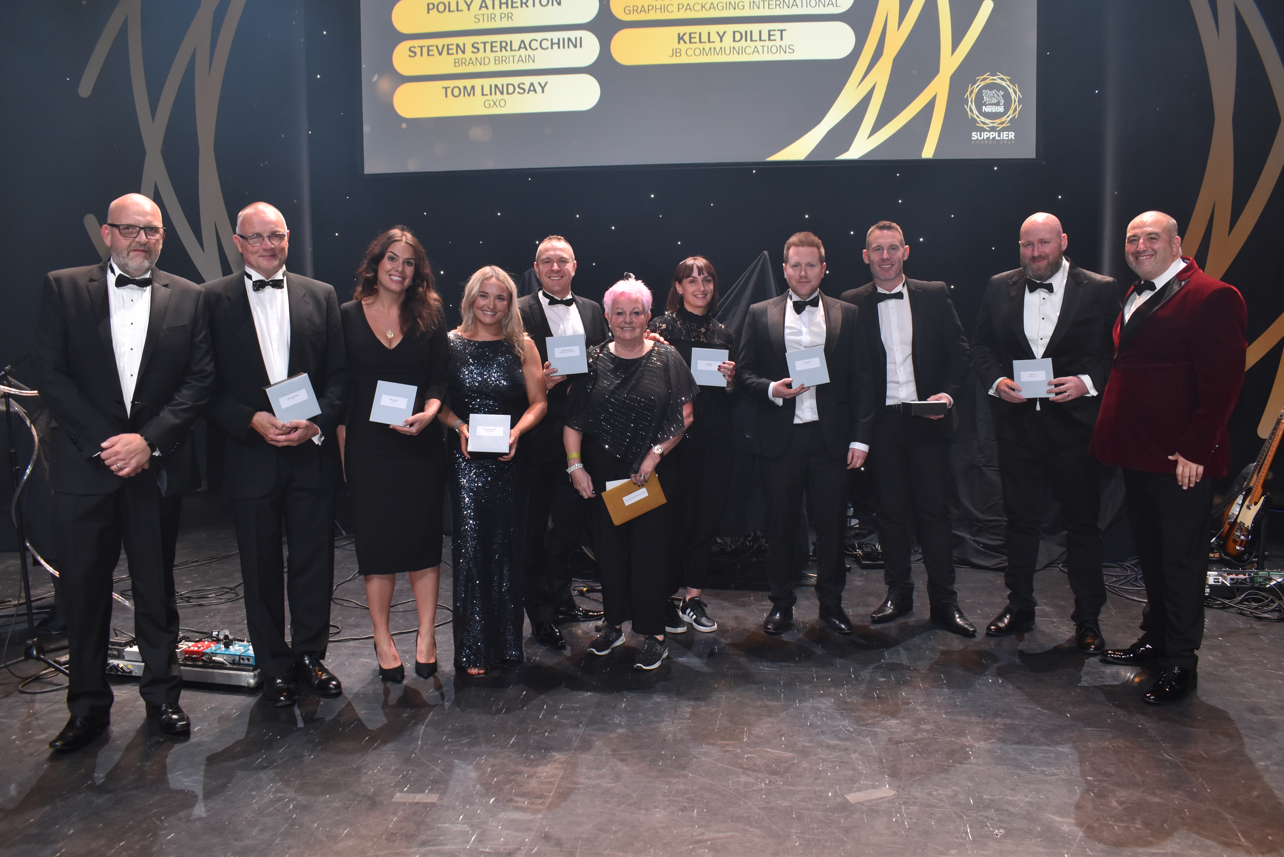 Eleven people on stage and surrounding an award.