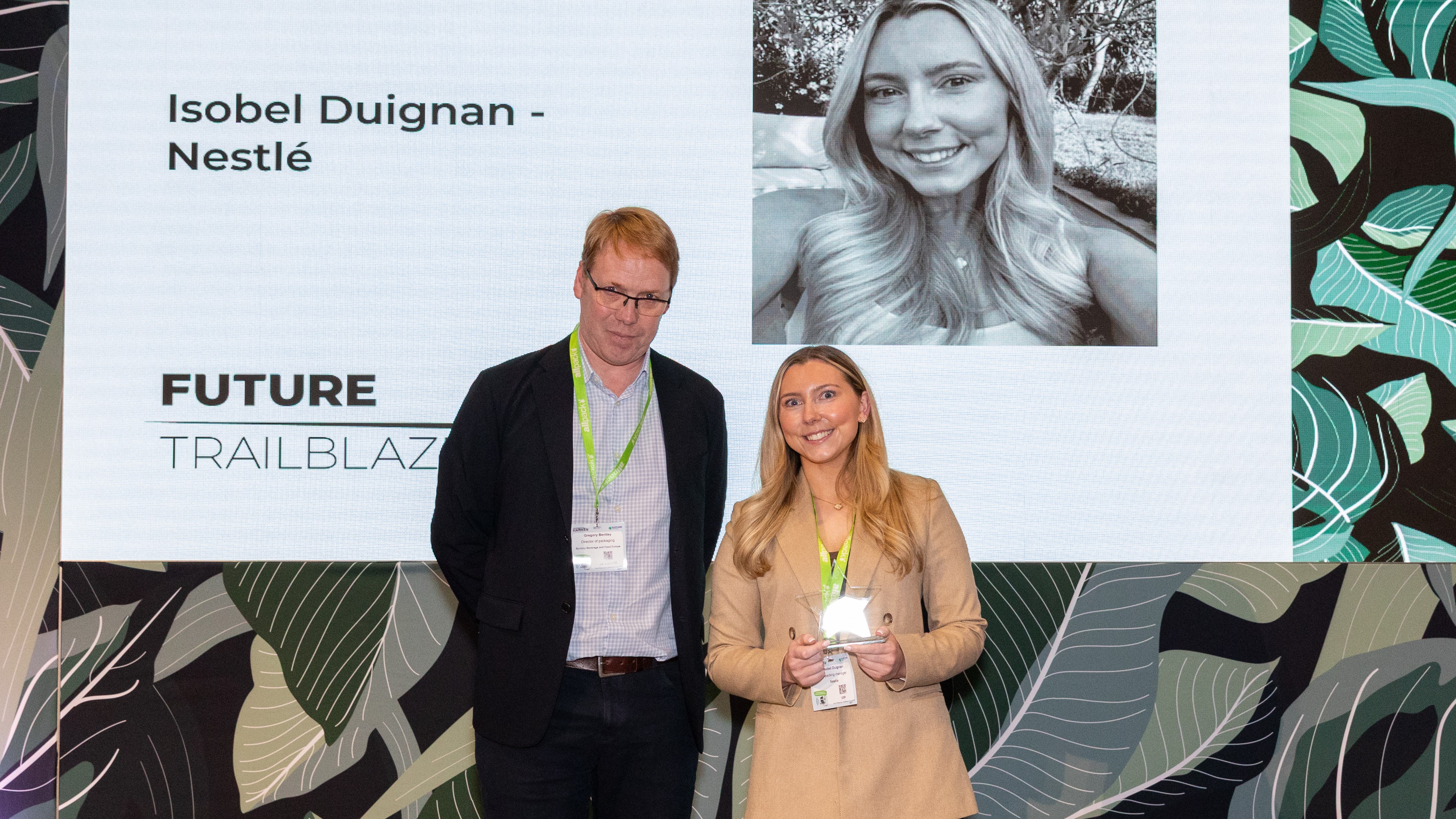 Two people standing on stage during an awards ceremony recognising Isobel Duignan.