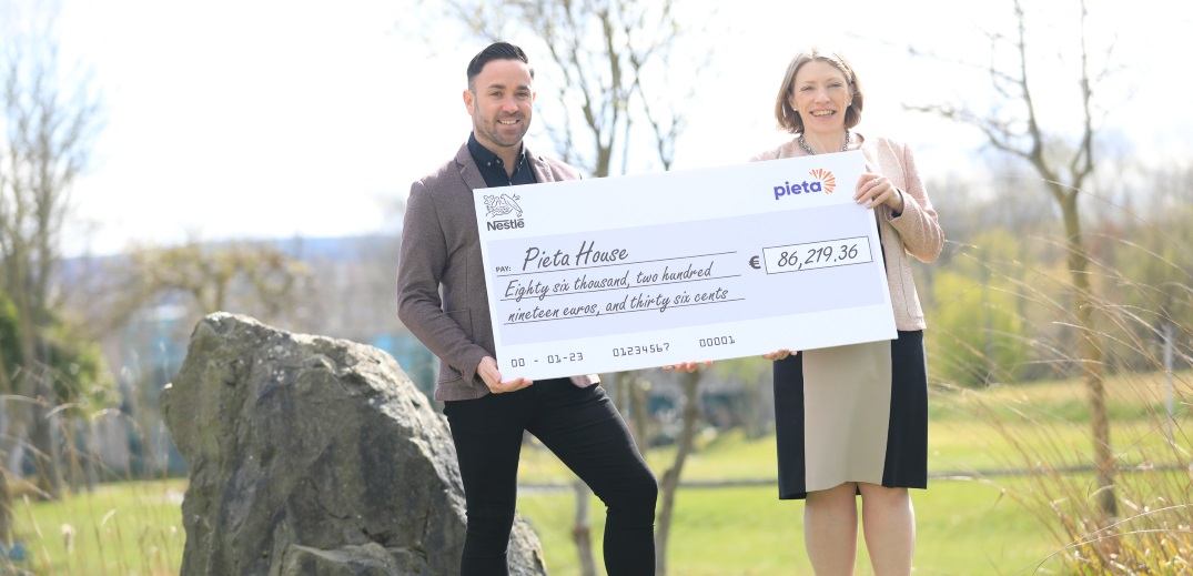 man and woman stood outdoors holding a cheque