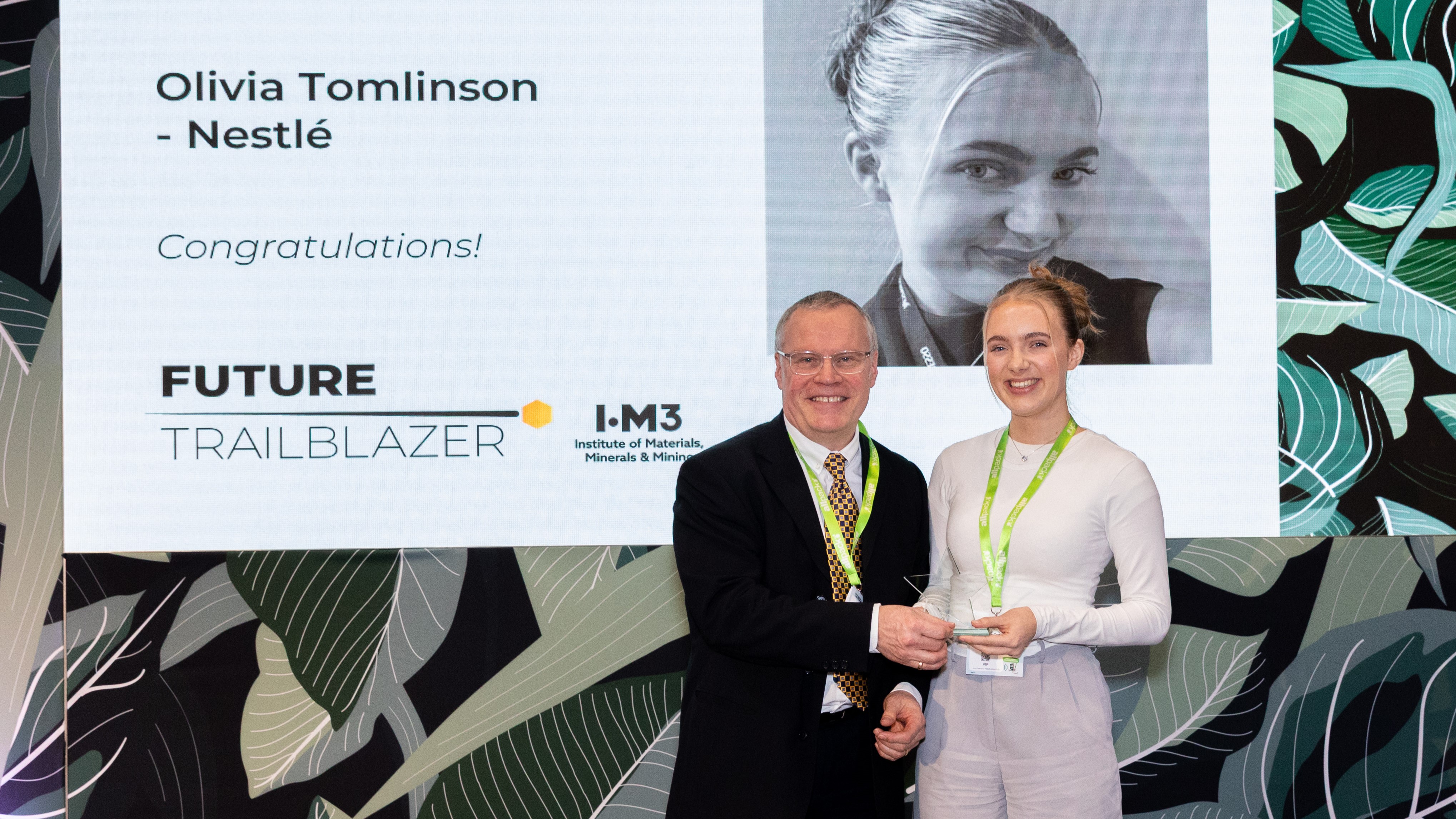 Two people standing on stage during an awards ceremony recognising Olivia Tomlinson.