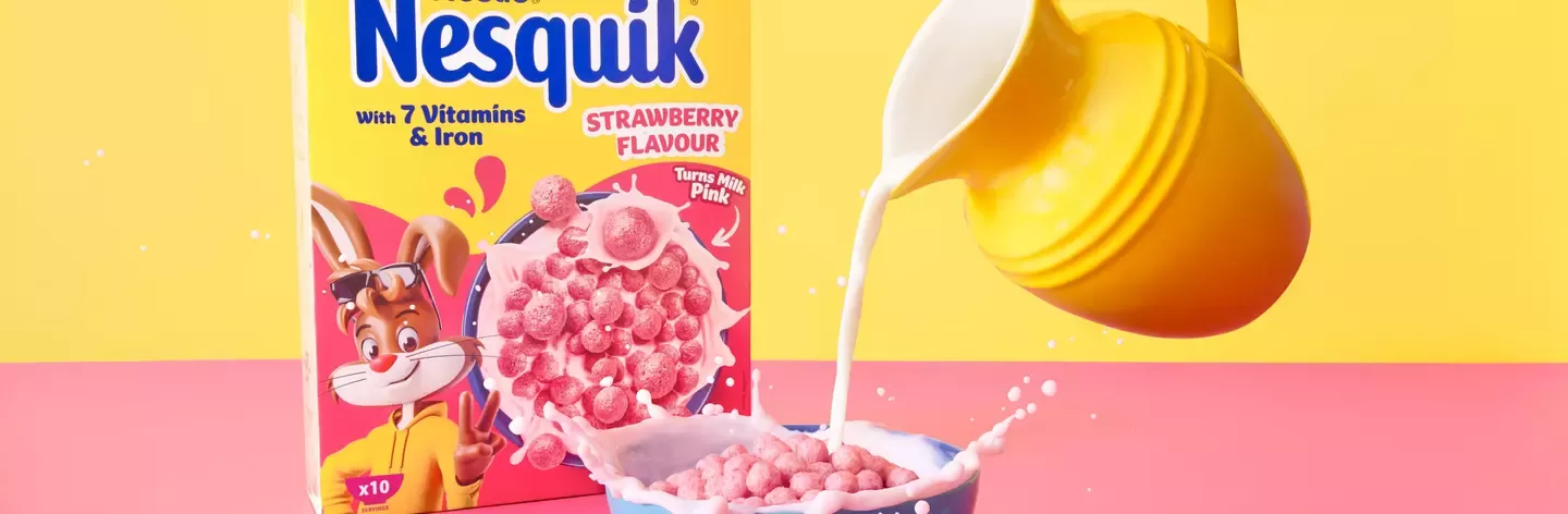 Milk being poured into a bowl of Nestquik Strawberry cereal