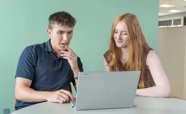 Two people working together on a laptop