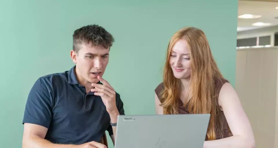 Two people working together on a laptop
