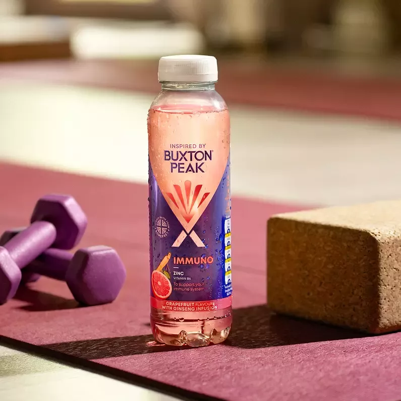 Bottle of water sitting on yoga matt next to weights.