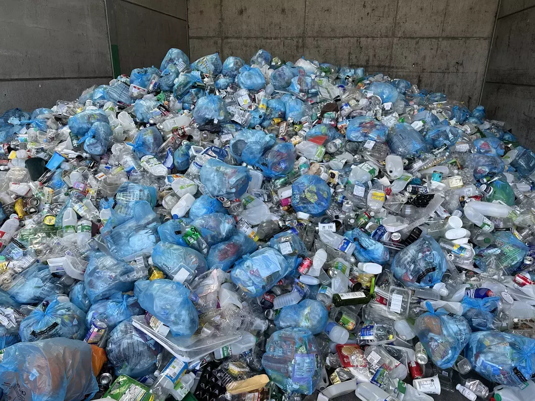 Large pile of plastics including blue plastic bin bags. 
