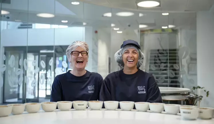 Two women laughing with a row of cups in front of them