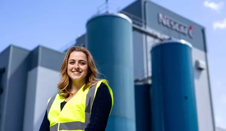 Emilie standing in front of the Nescafé factory wearing a high vis jacket
