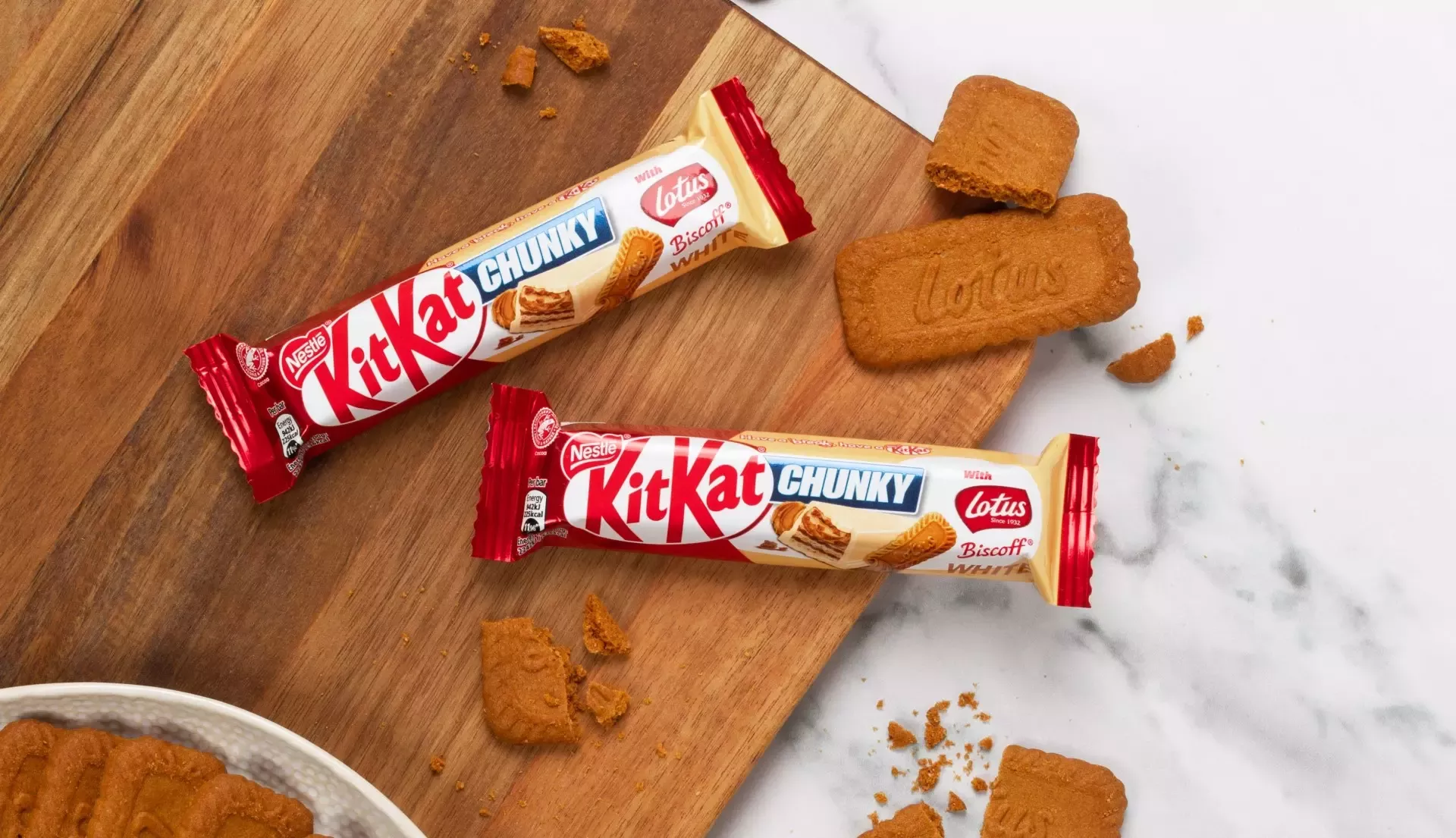 KitKat Chunky White with Lotus Biscoff on a wooden chopping board with crumbled lotus biscuits