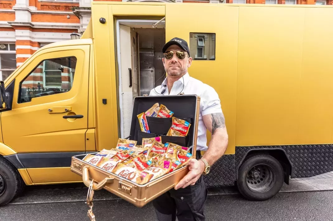 Jason Fox holds a golden case in front of a golden security van full of the new Golden Collection range