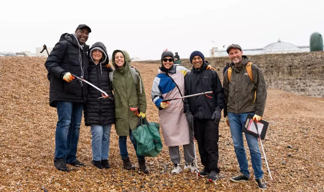 Six Nestlé employees stand on Brighton Beach with litter pickers and rubbish bags