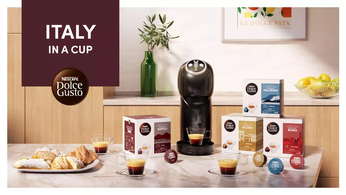 A coffee machine, boxes of coffee pods, two cups and croissants on a kitchen worktop.