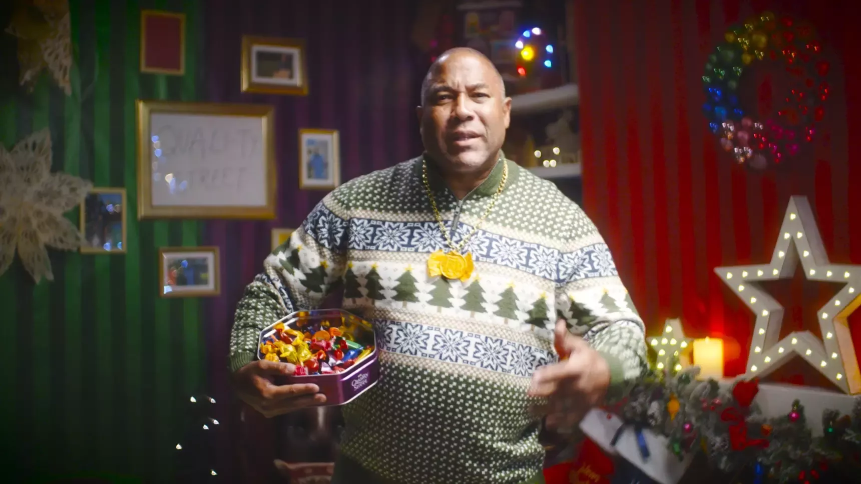 Footballing legend John Barnes holds a tin of Quality Street in festive living room
