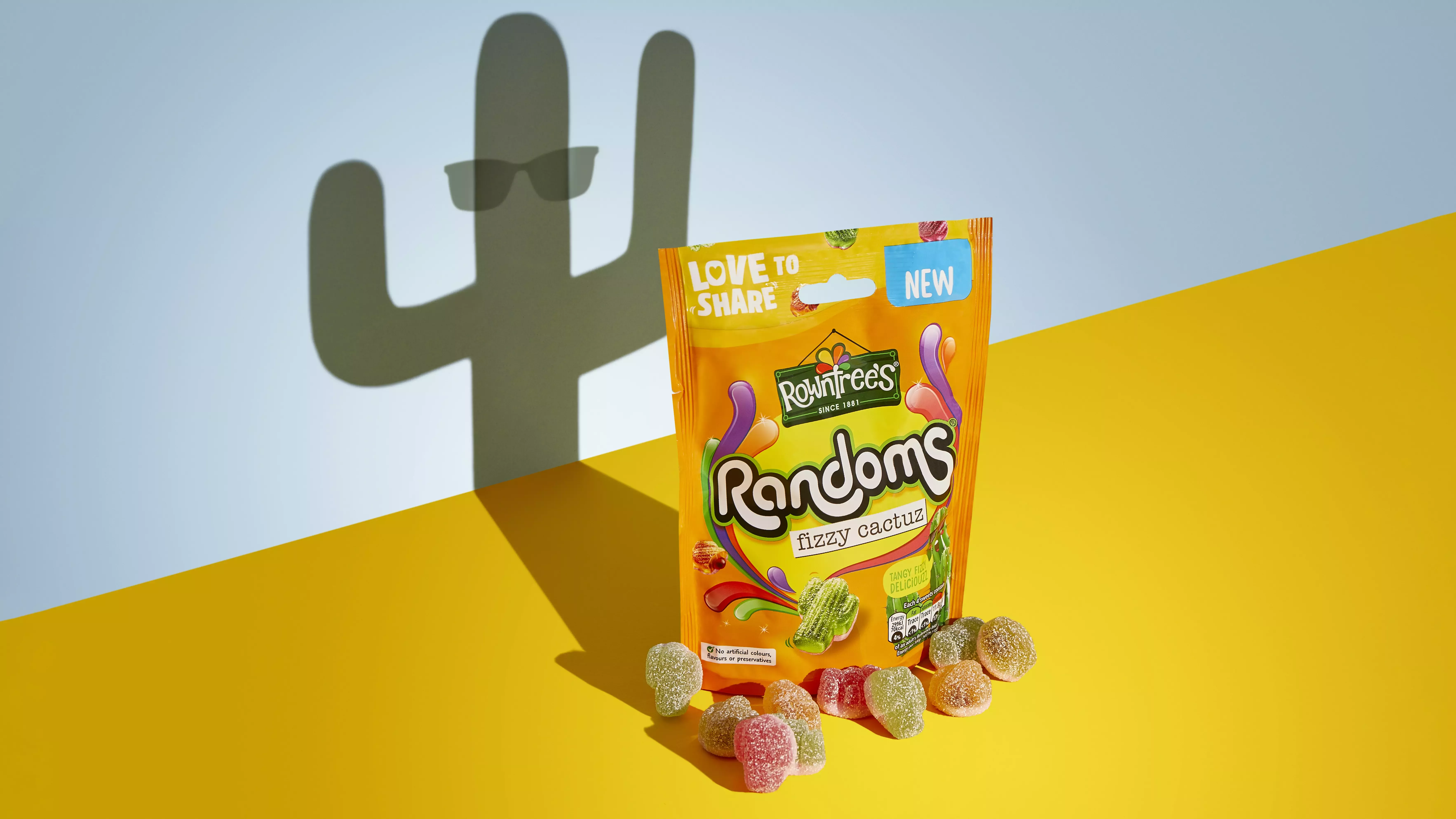 An orange packet of sweets, with some colourful sweets sitting in front of it, and a cactus-shaped shadow behind it.