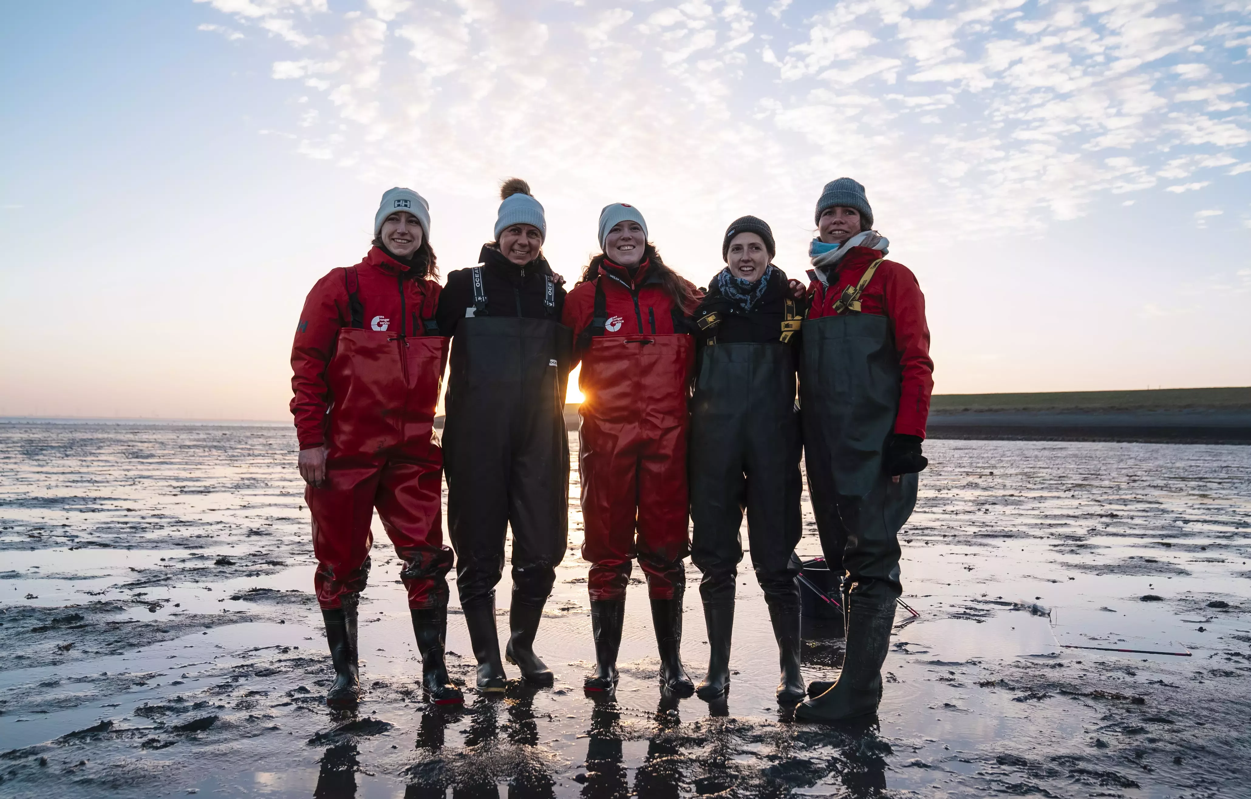 A group of five sea rangers standing together against an ocean backdrop.
