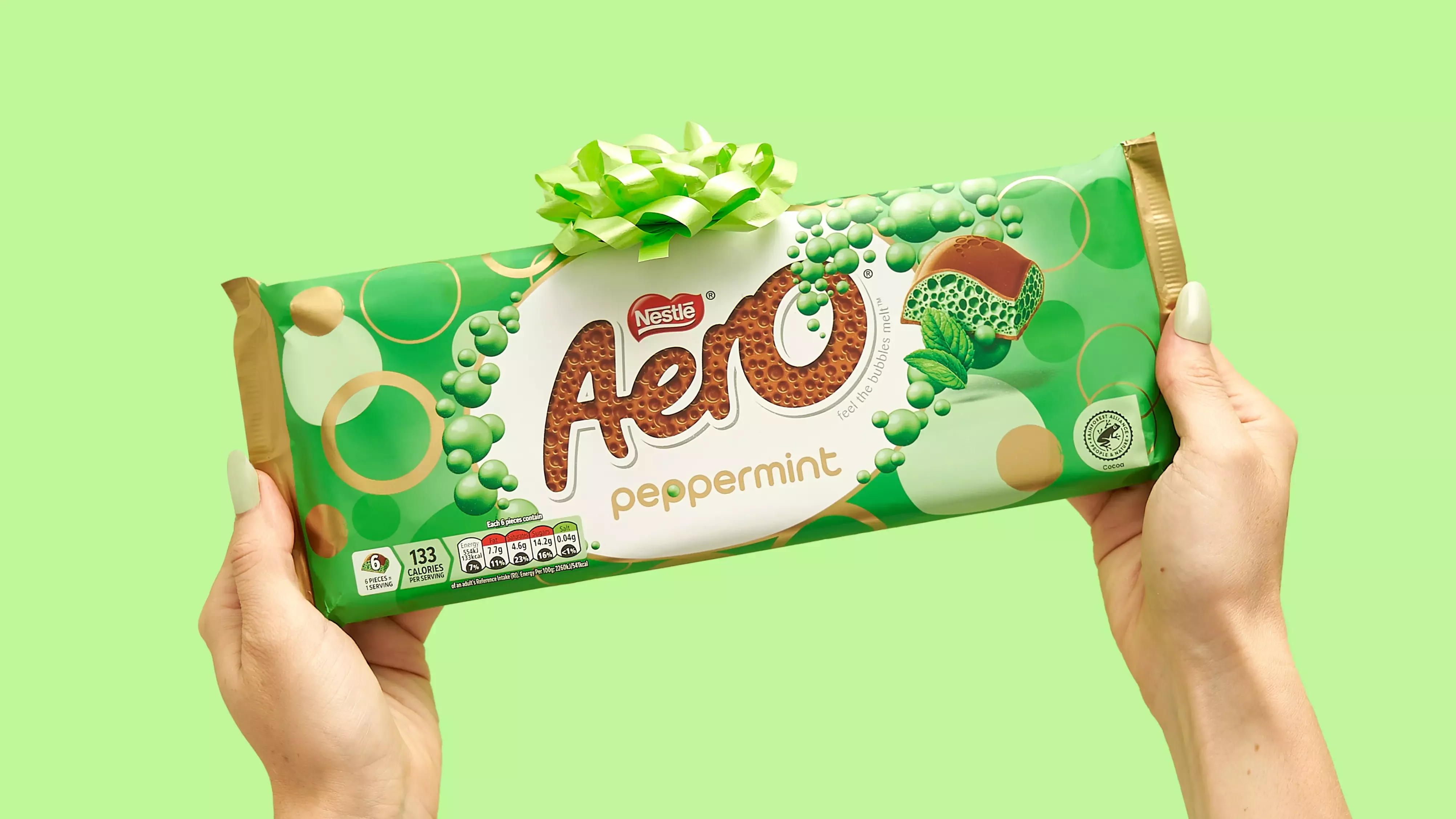 An image of an Aero sharing bar being held in two hands against a light green backdrop. The sharing bar has a bow on top.