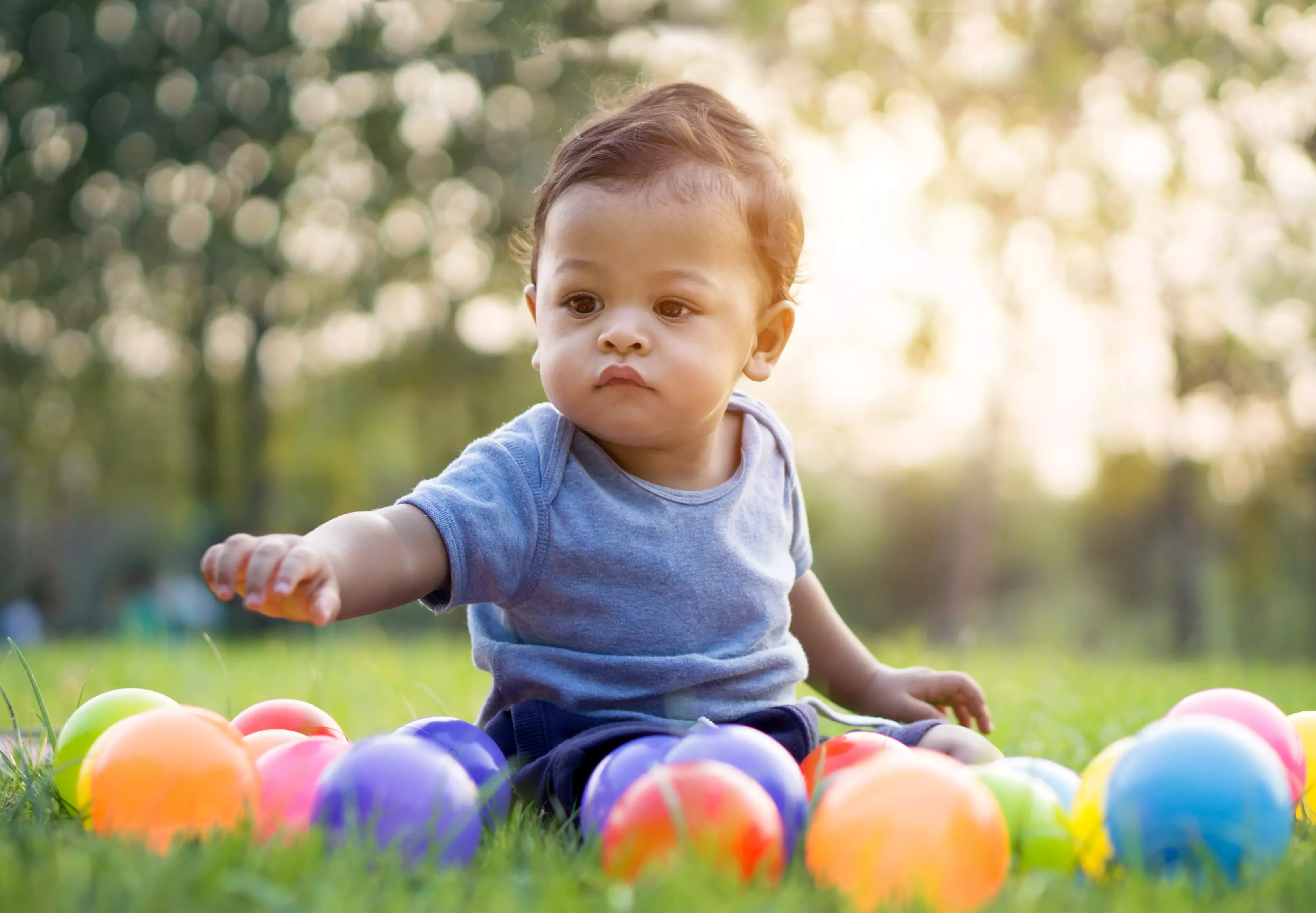 Baby playing outside with coloured balls