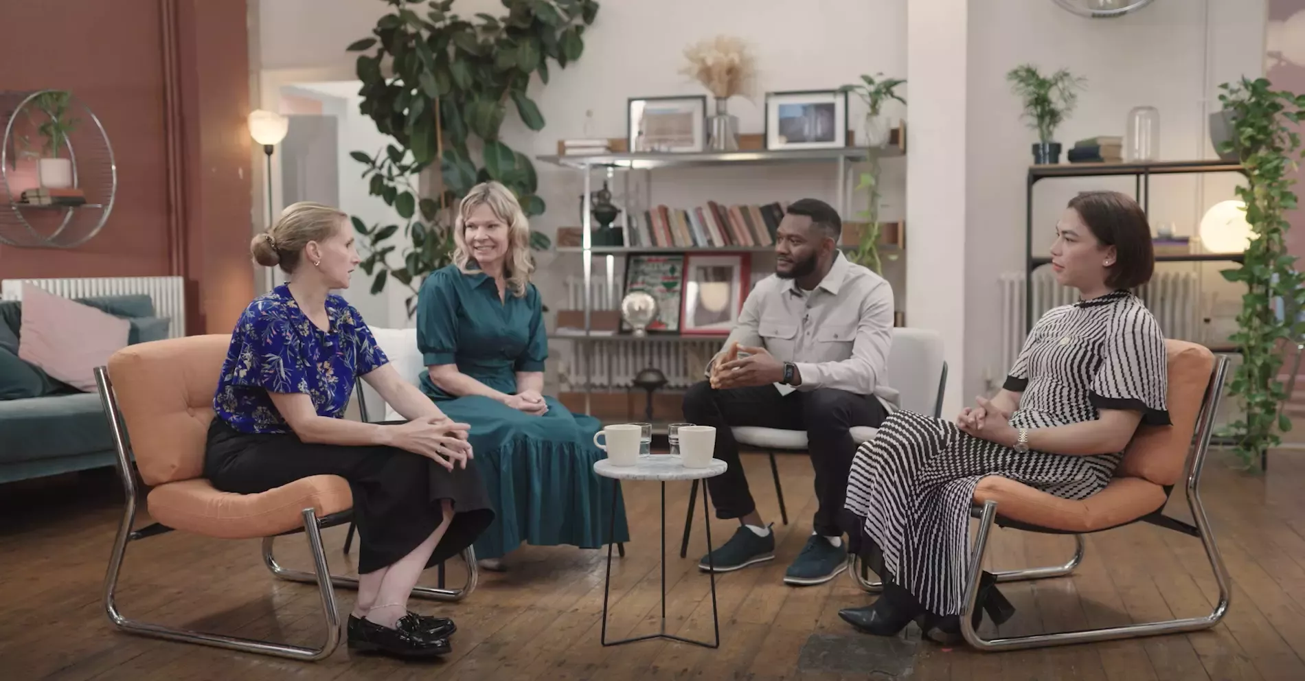 Three women and a man sat on chairs in a circle chatting