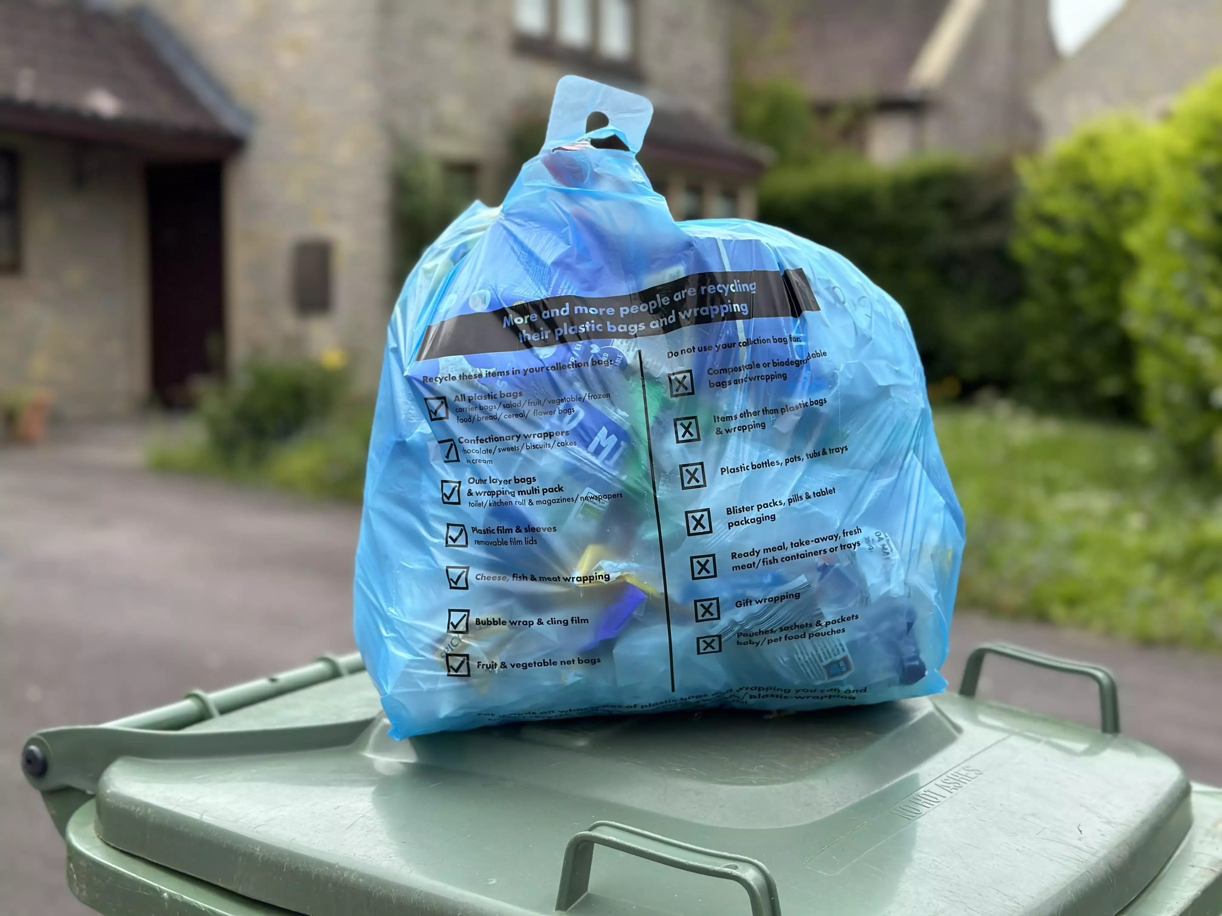 A blue bin bag sitting on top of a green bin.