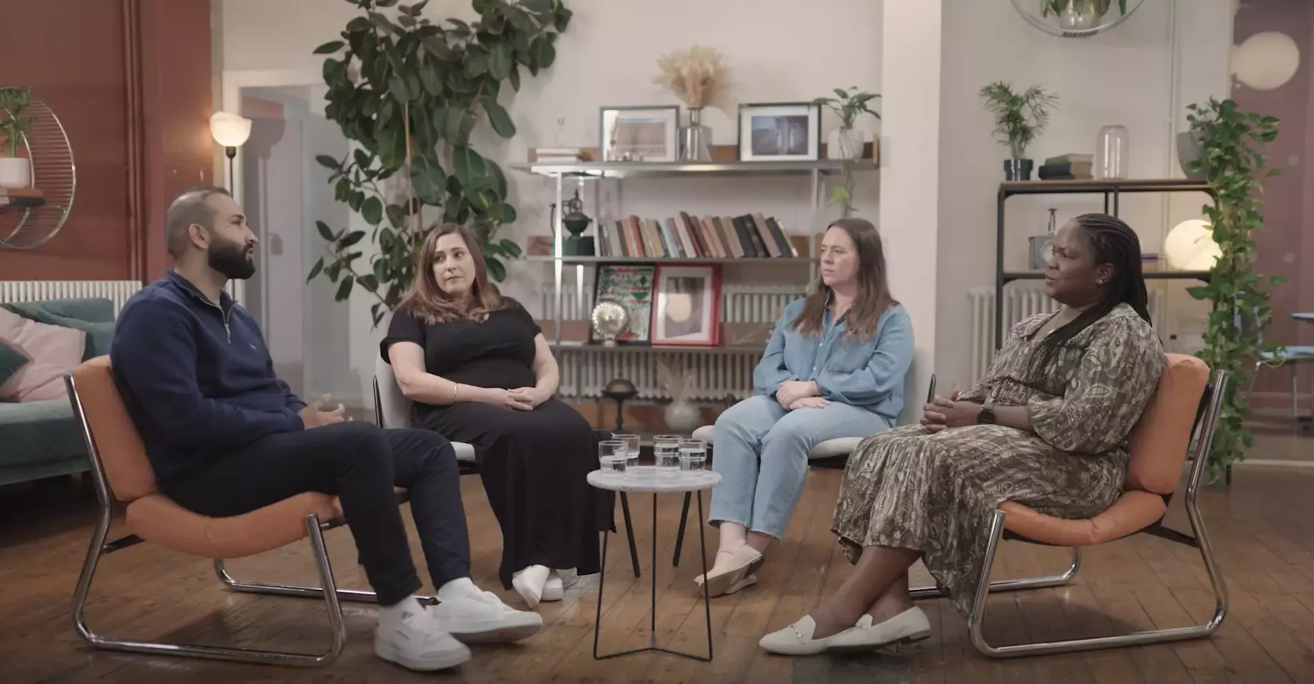 Three women and a man sat on chairs in a circle chatting for parent support group