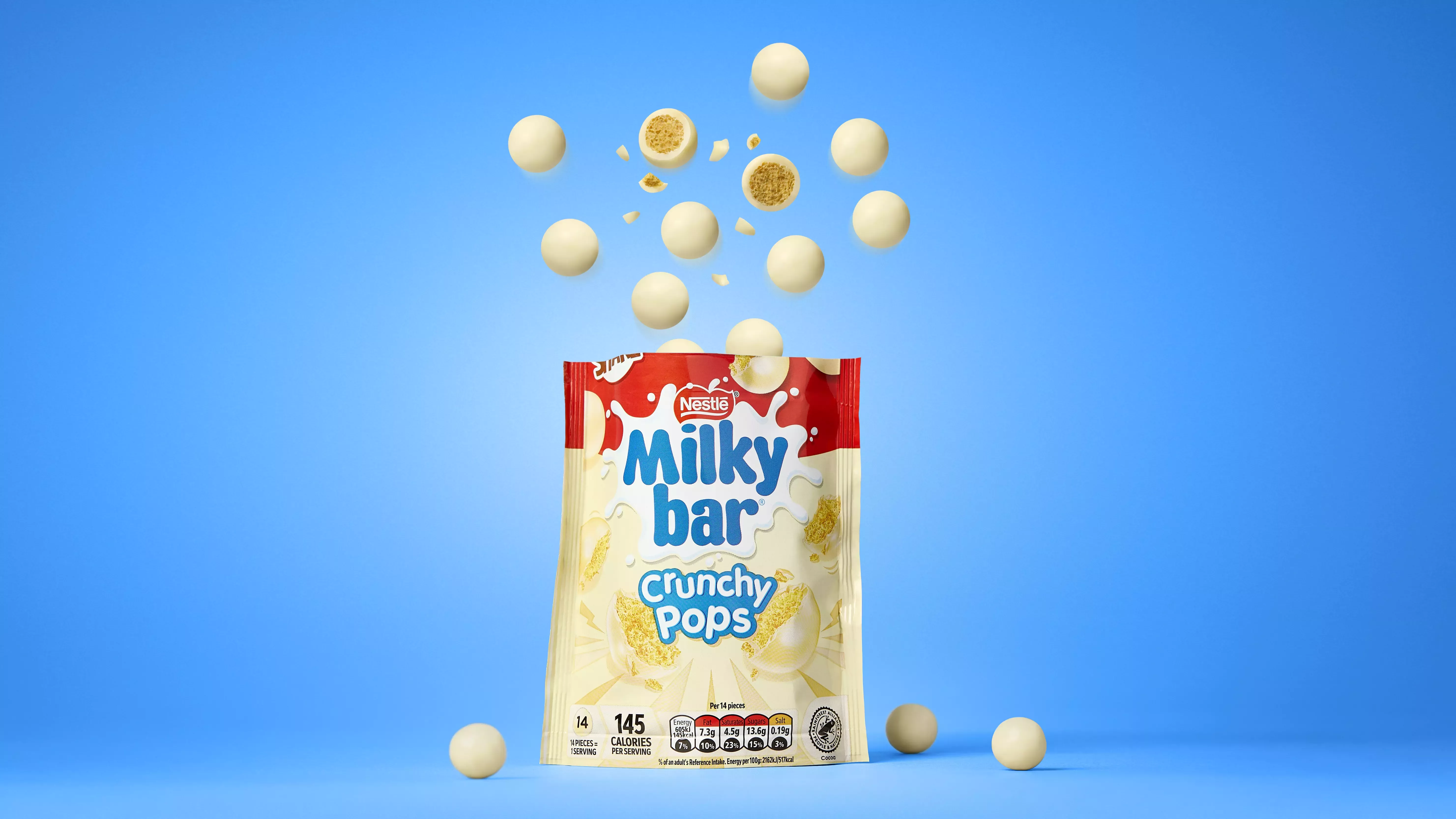 Milkybar Crunchy Pops jumping out of the packet with a blue background