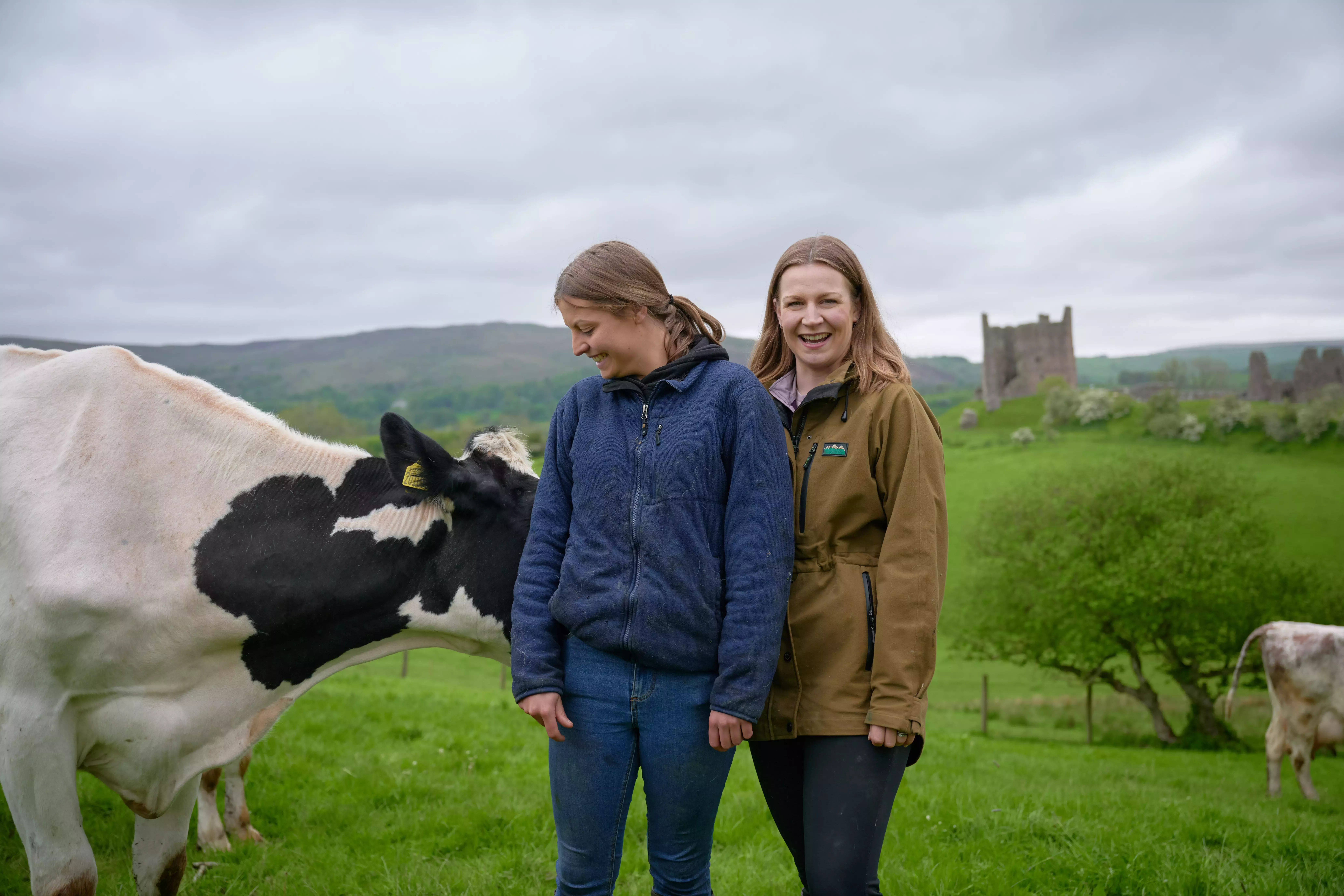 Two women standing in a farm with a cow