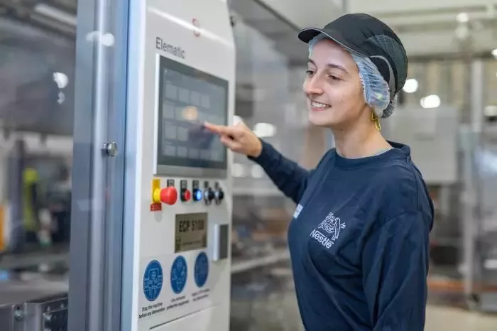 Nestlé employee operating a touchscreen control panel in a production facility